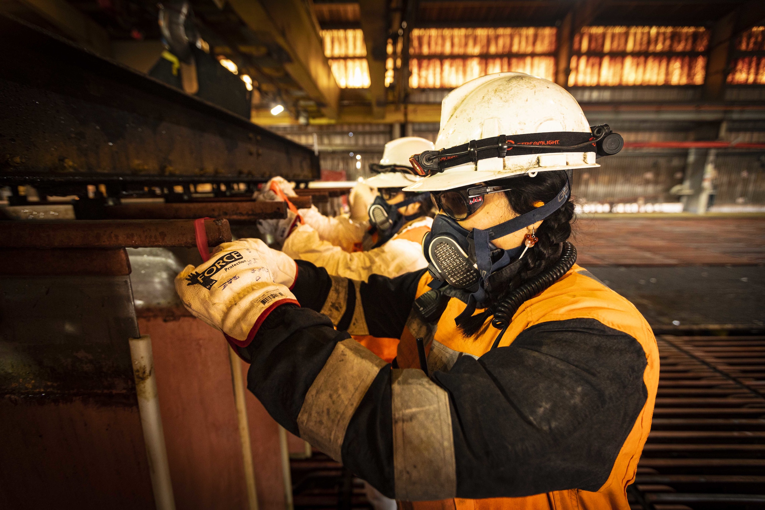 Workers in protective gears are operating machine in a workshop