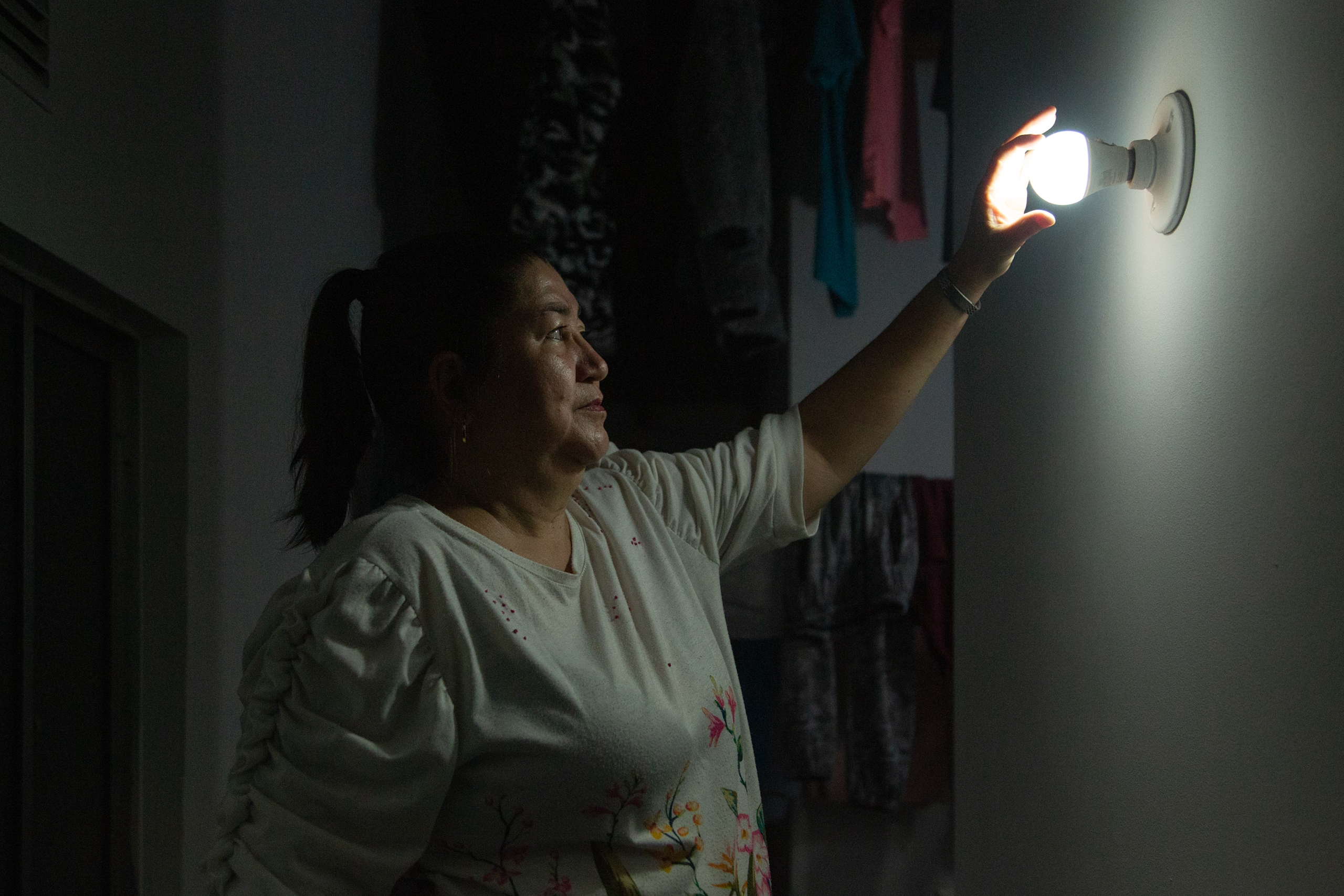 Beatriz Tamayo, moradora de La Estrecha, troca uma lâmpada em sua casa