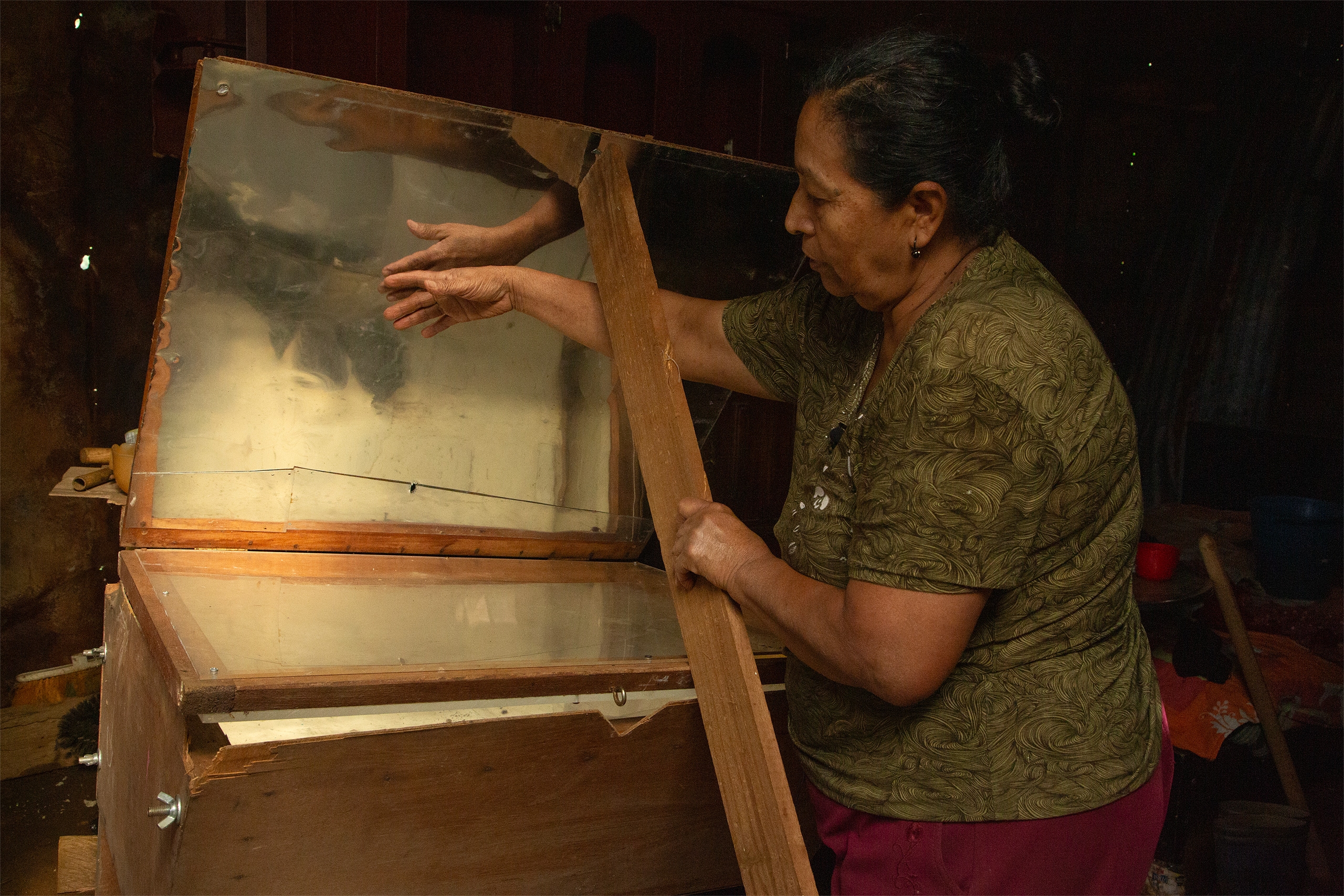 Esneda Ramírez segura um pedaço de madeira para manter o forno aberto no processo de desidratação de plantas aromáticas