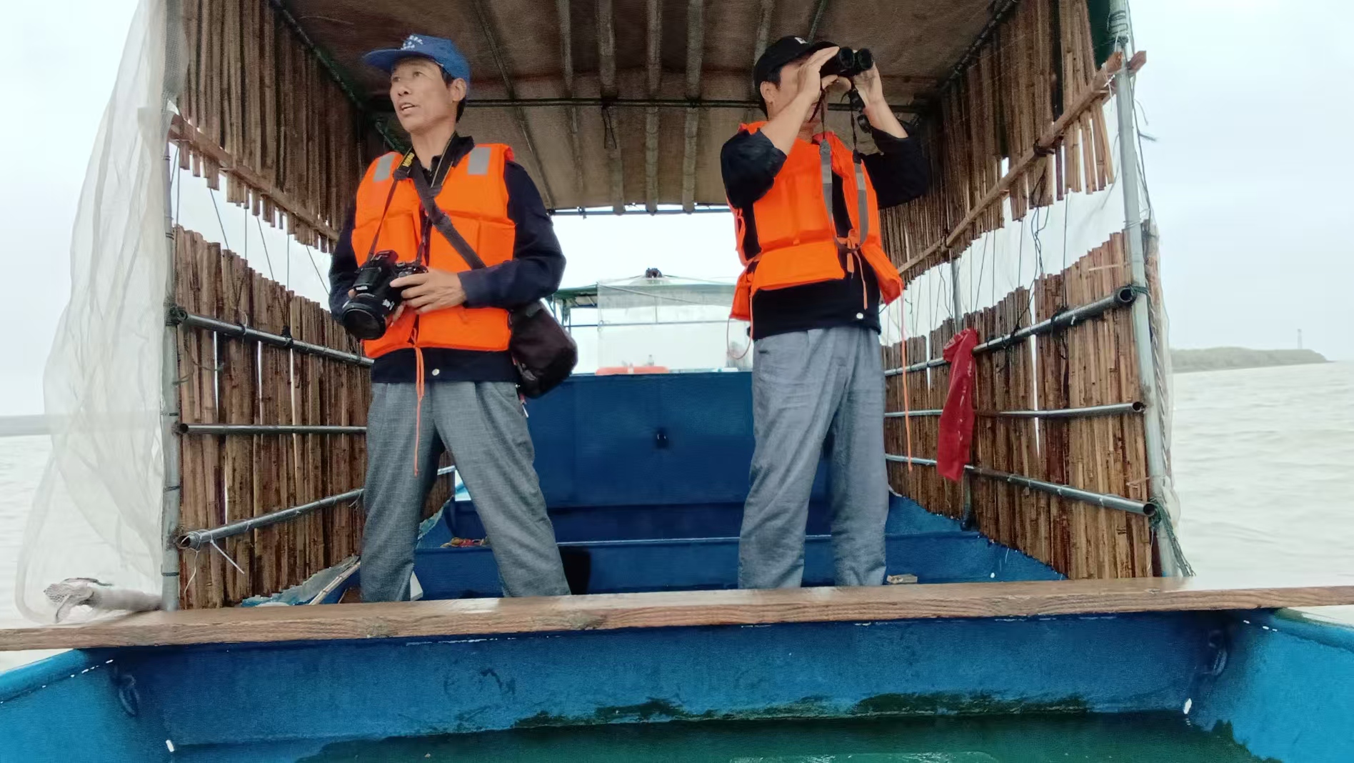 two people on the boat doing porpoise monitoring work at a lake