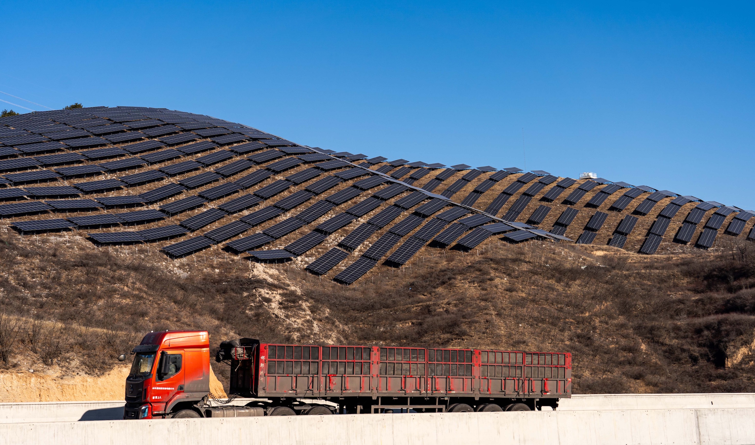 A coal truck passes by a photovoltaic power plant in Shanxi