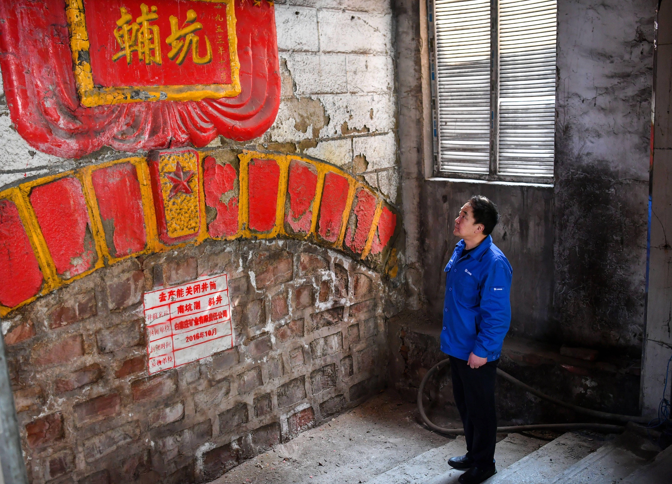 a worker stands in front of a closed mine tunnel at a coal site