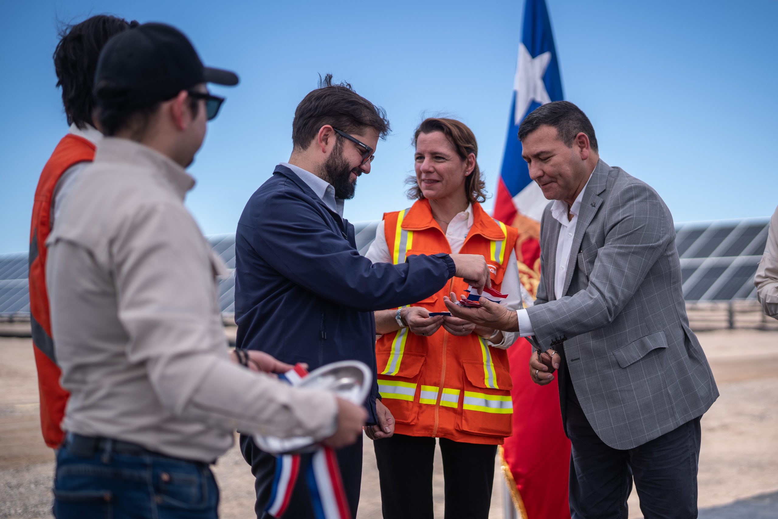 Gabriel Boric parado junto a otras personas delante de un parque de energía solar
