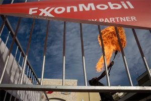 plume of fire seen from behind bars with exonmobil sign attached