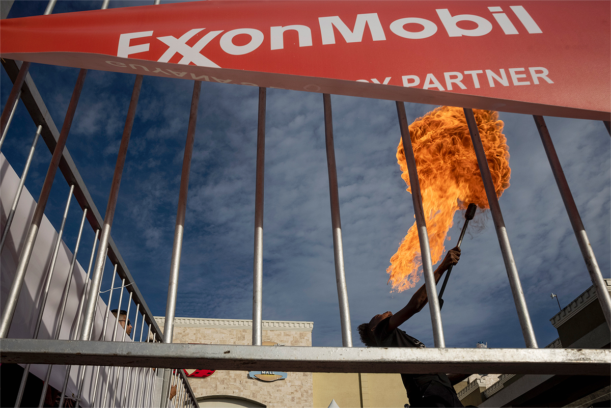 plume of fire seen from behind bars with exonmobil sign attached