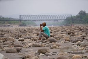 a man sit on a dry-out river