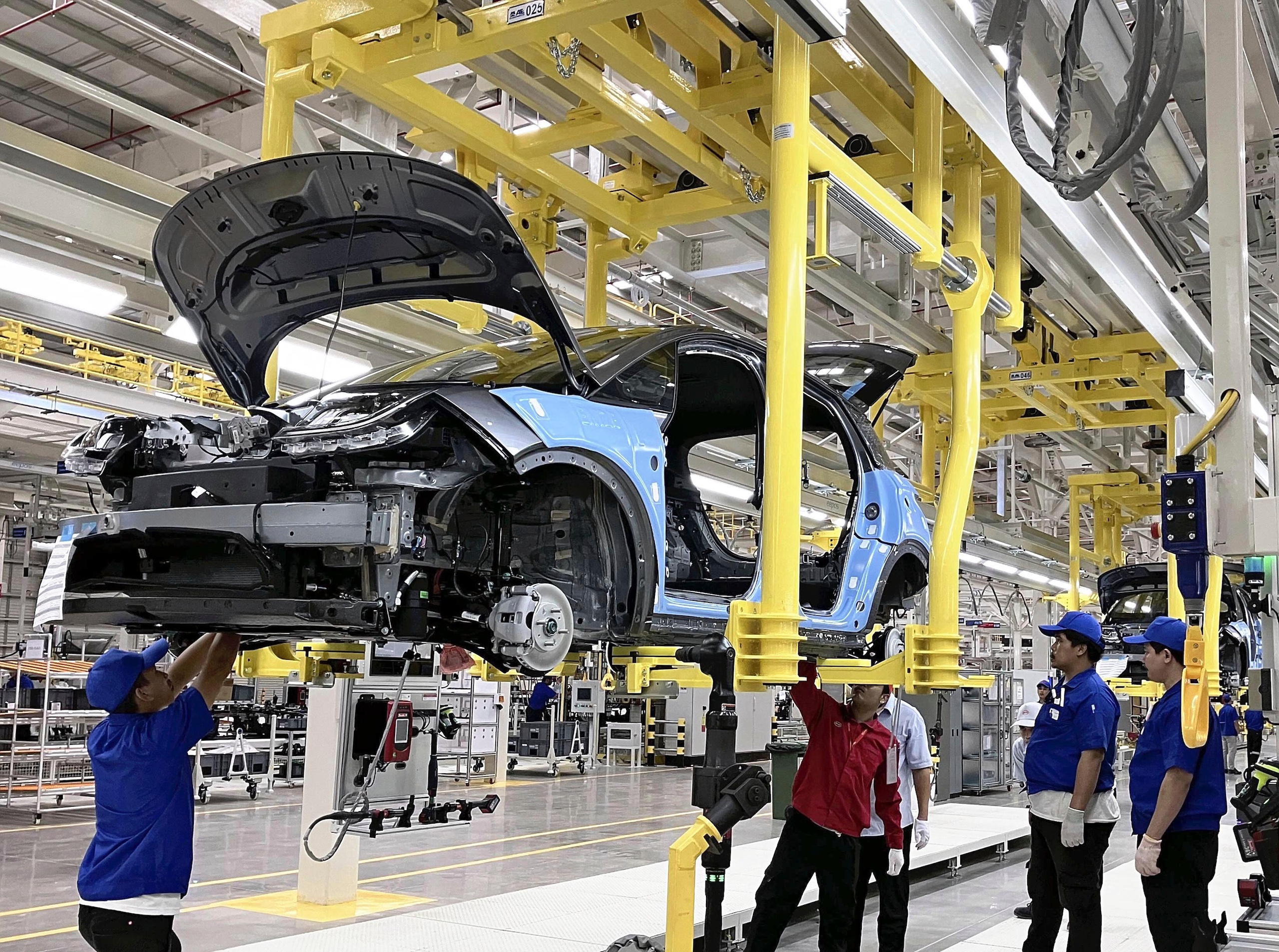 Workers manufacture an electric vehicle in a production line at a workshop