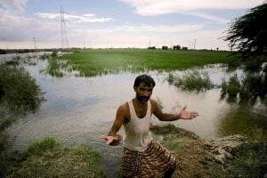 a farmer stands in his flooded farmland