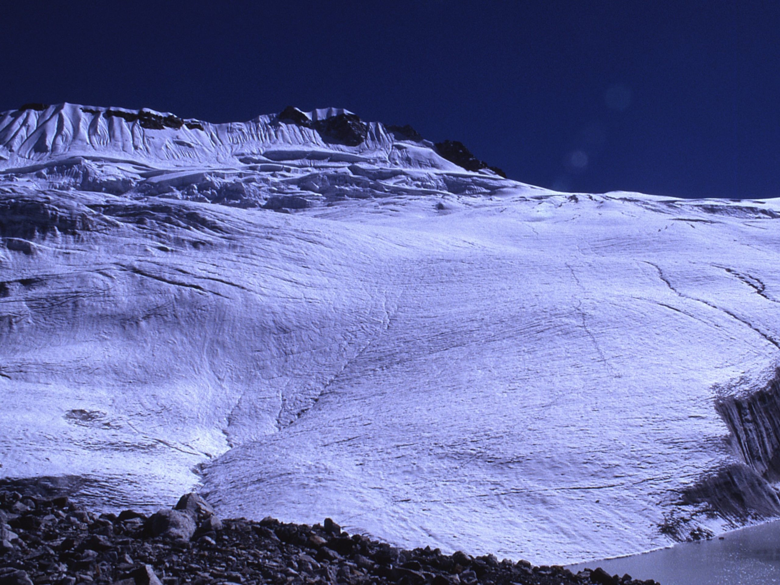 A snow-covered mountain peak rising against a cloudless sky