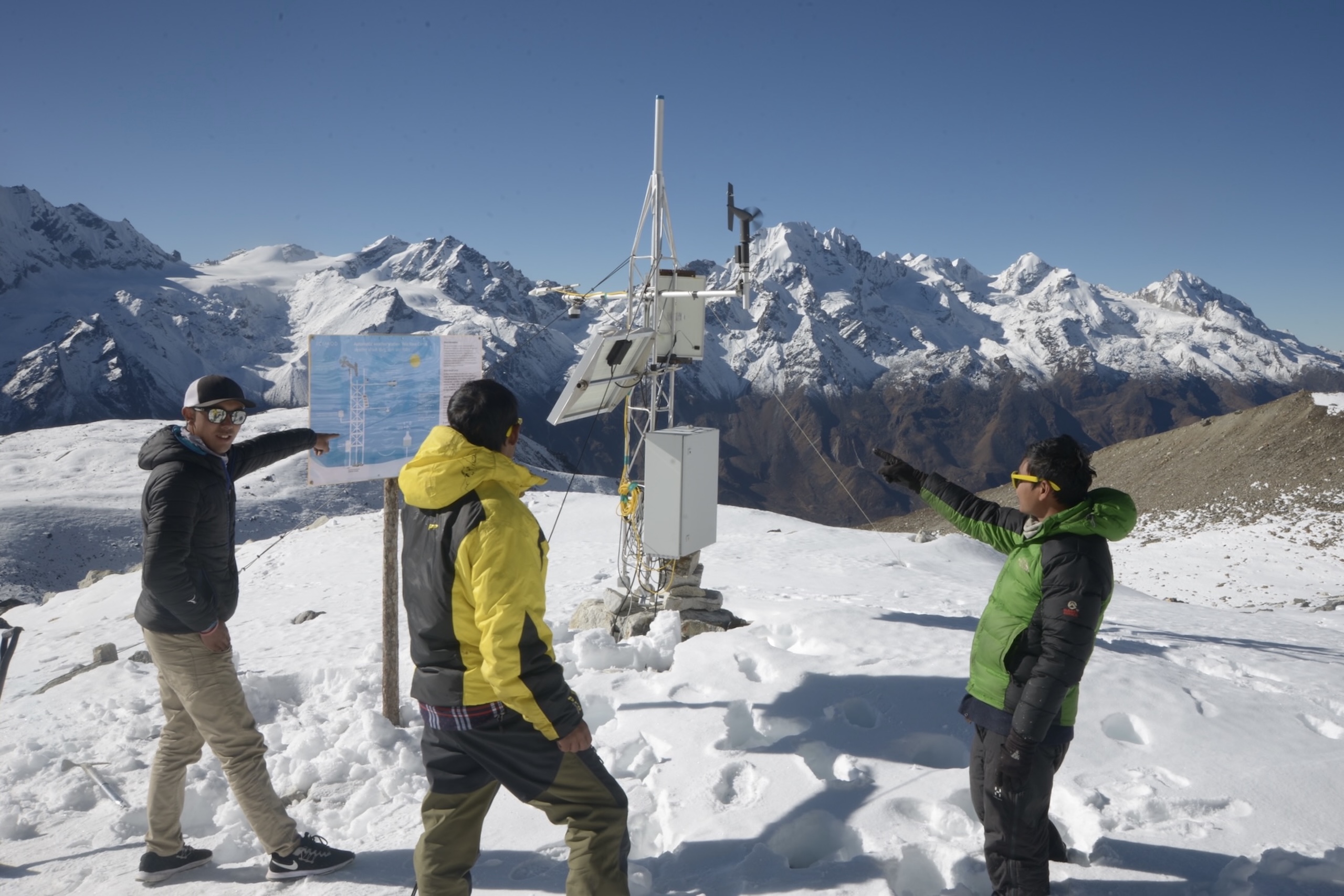 Three individuals standing on a snow-covered mountain peak