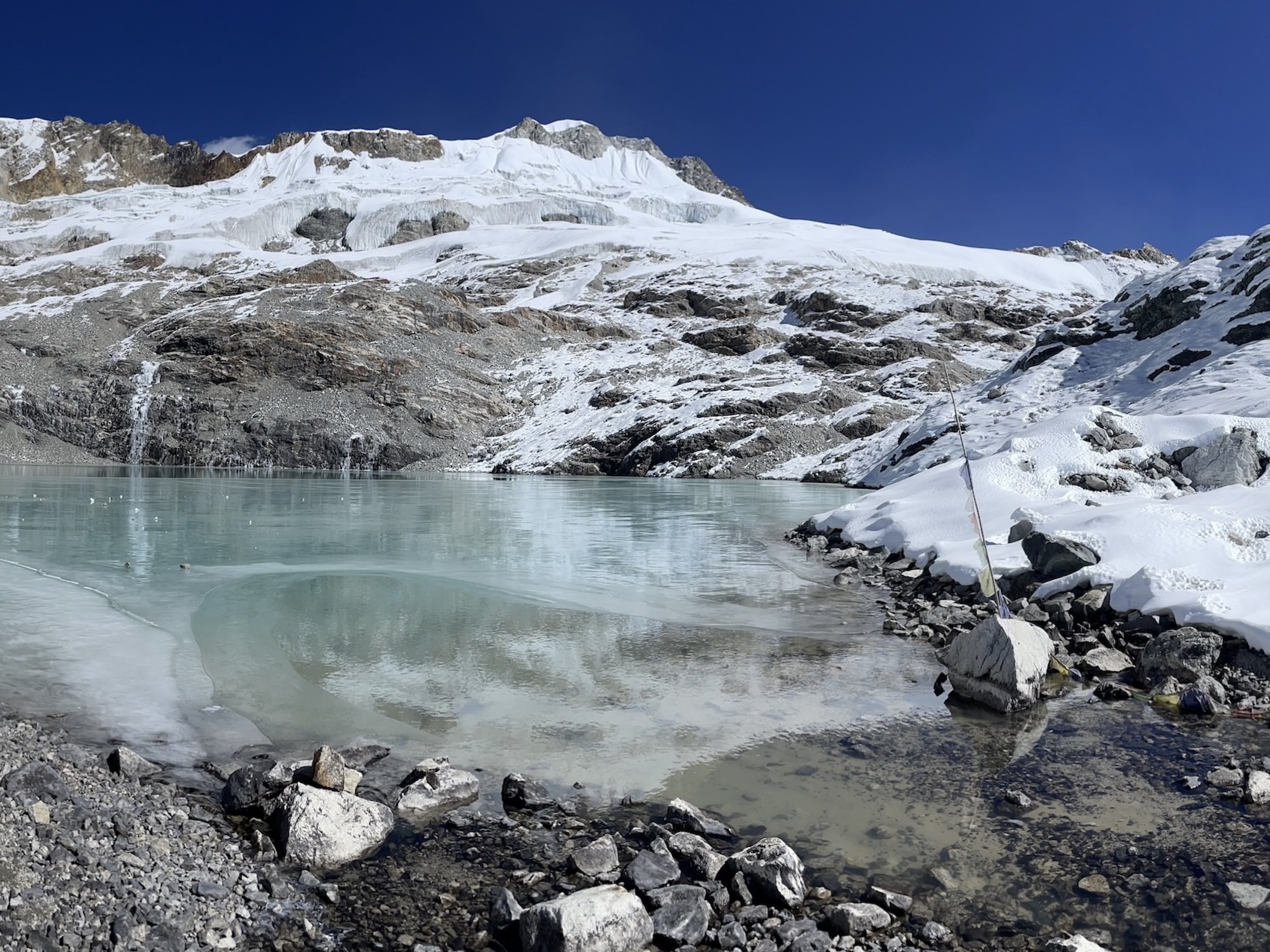 A lake surrounded by rocky terrain and a blanket of snow