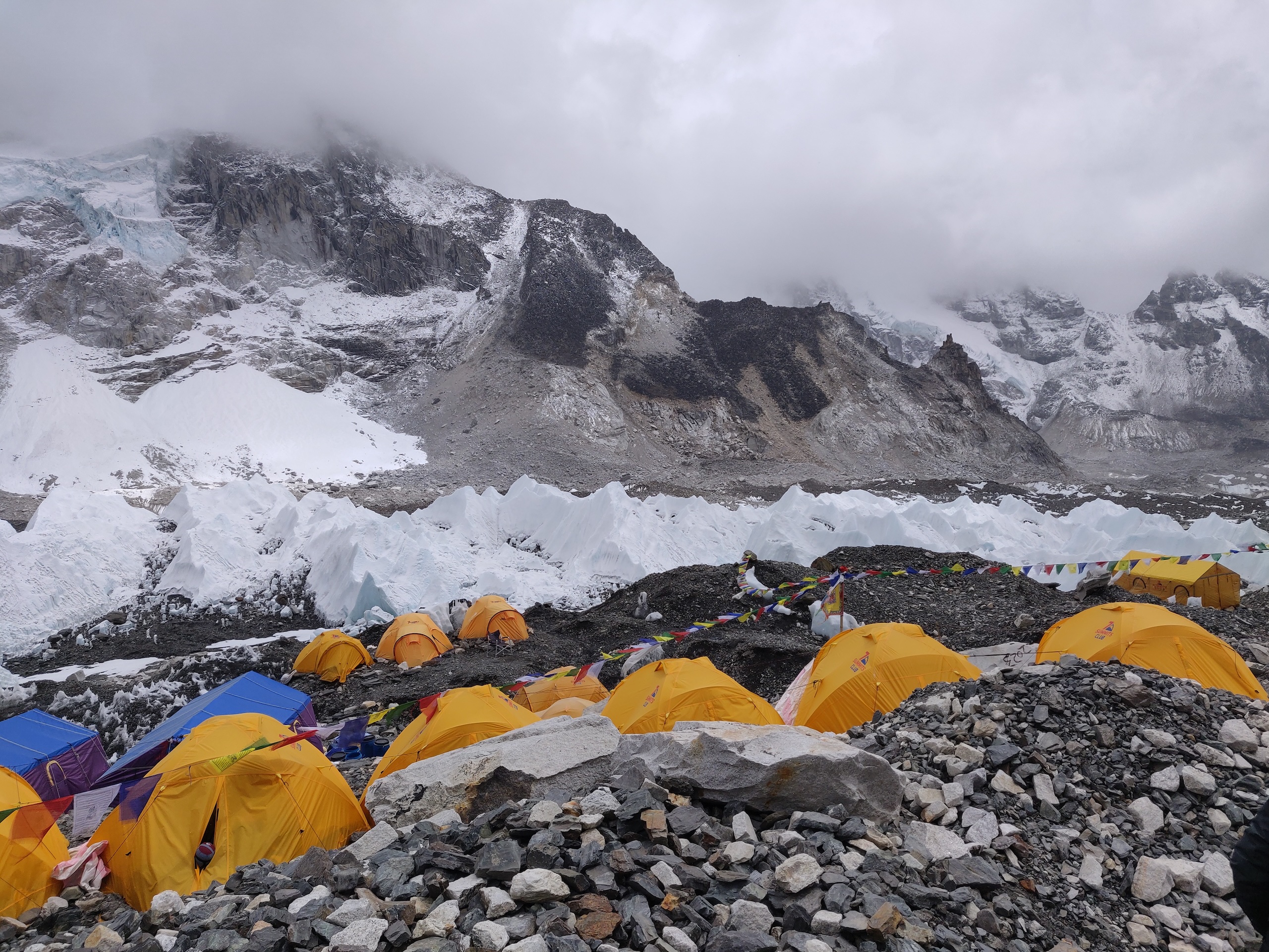 yellow tents on rocks near snow banks
