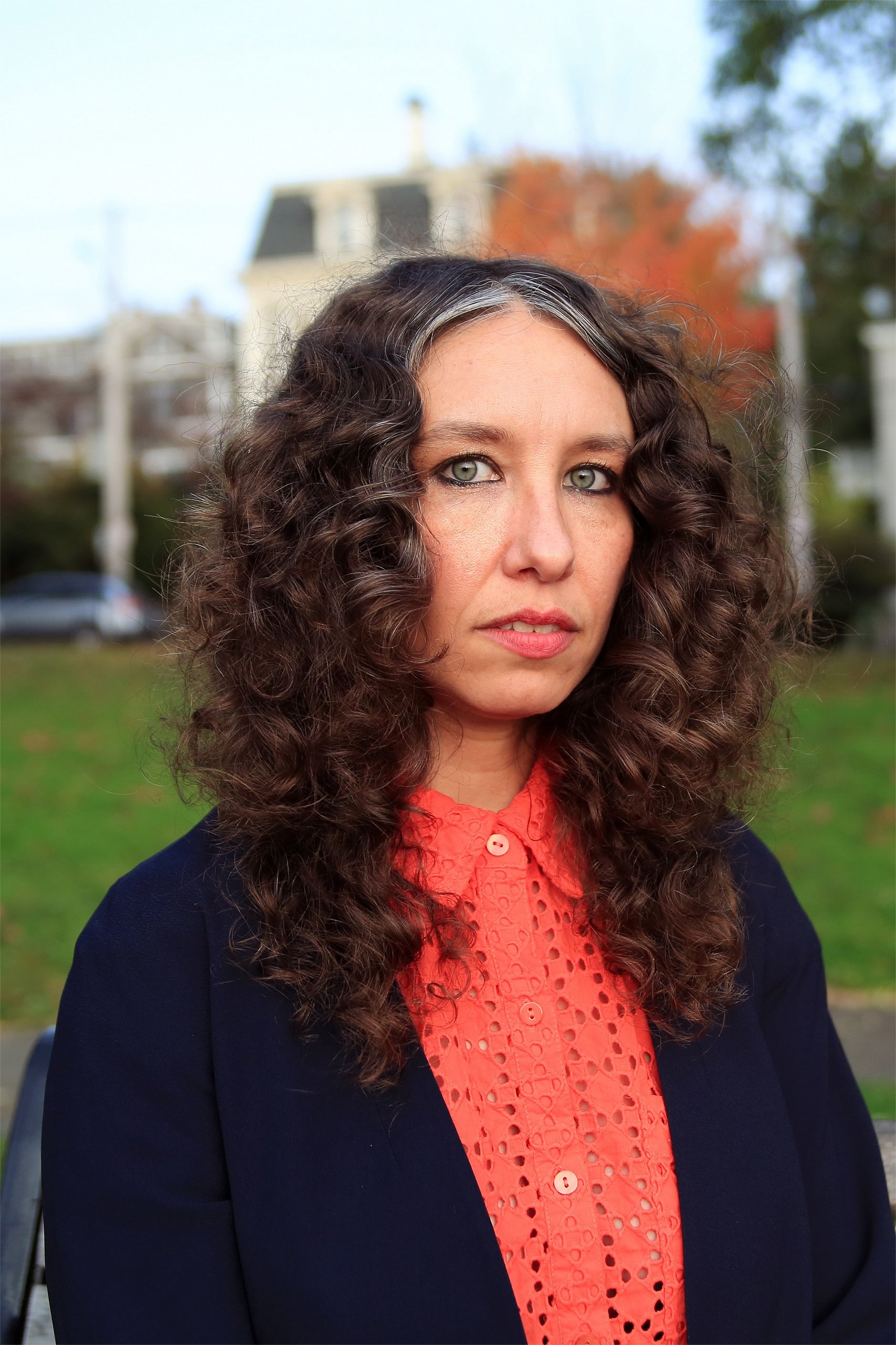 Thea Riofrancos, de cabelo castanho cacheado, pele branca e camisa rosa