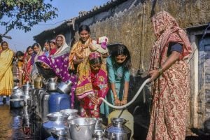 Women in Indian costume standing in queue to collect water