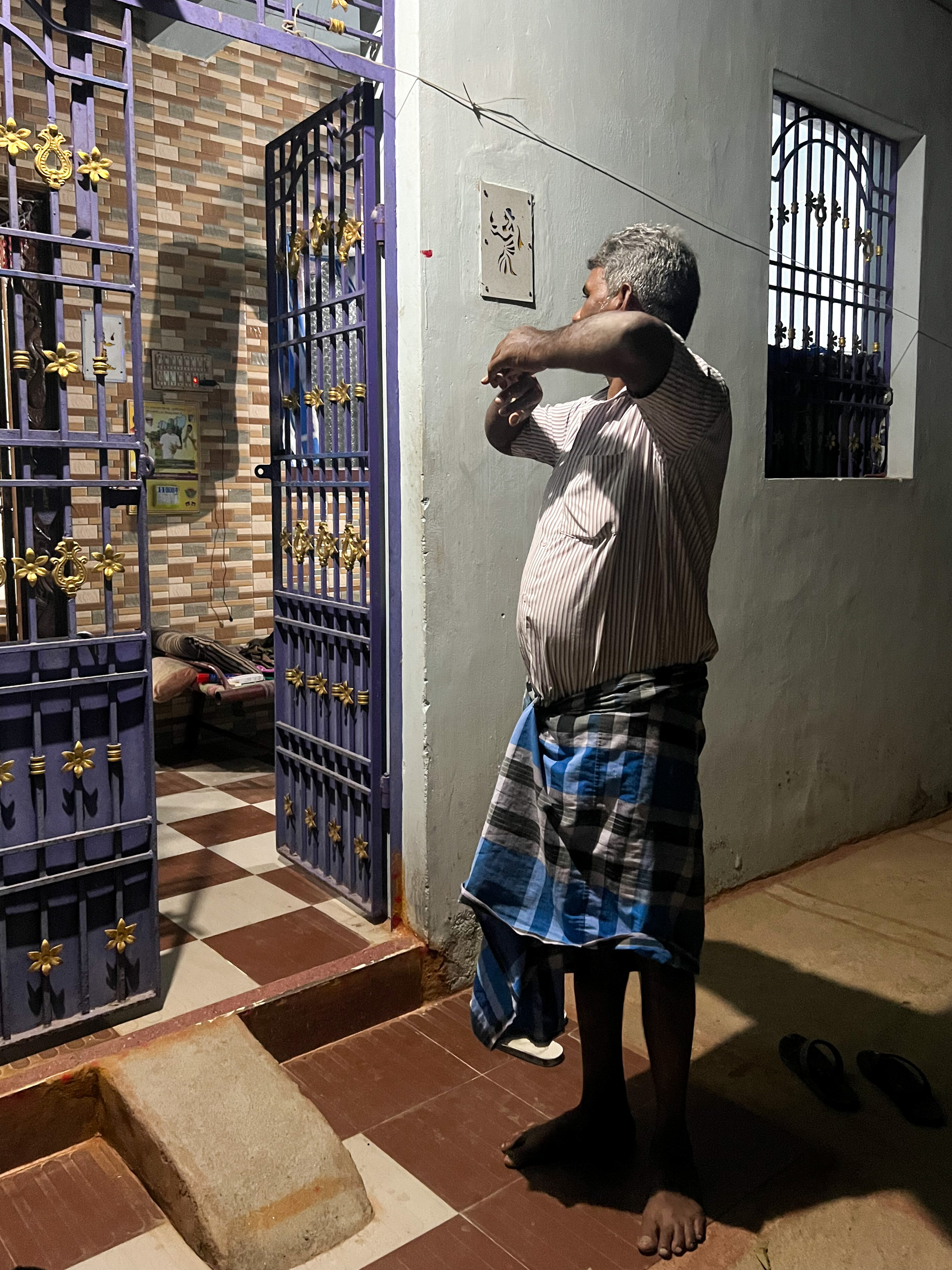 A man in a blue shirt stands in front of a closed door