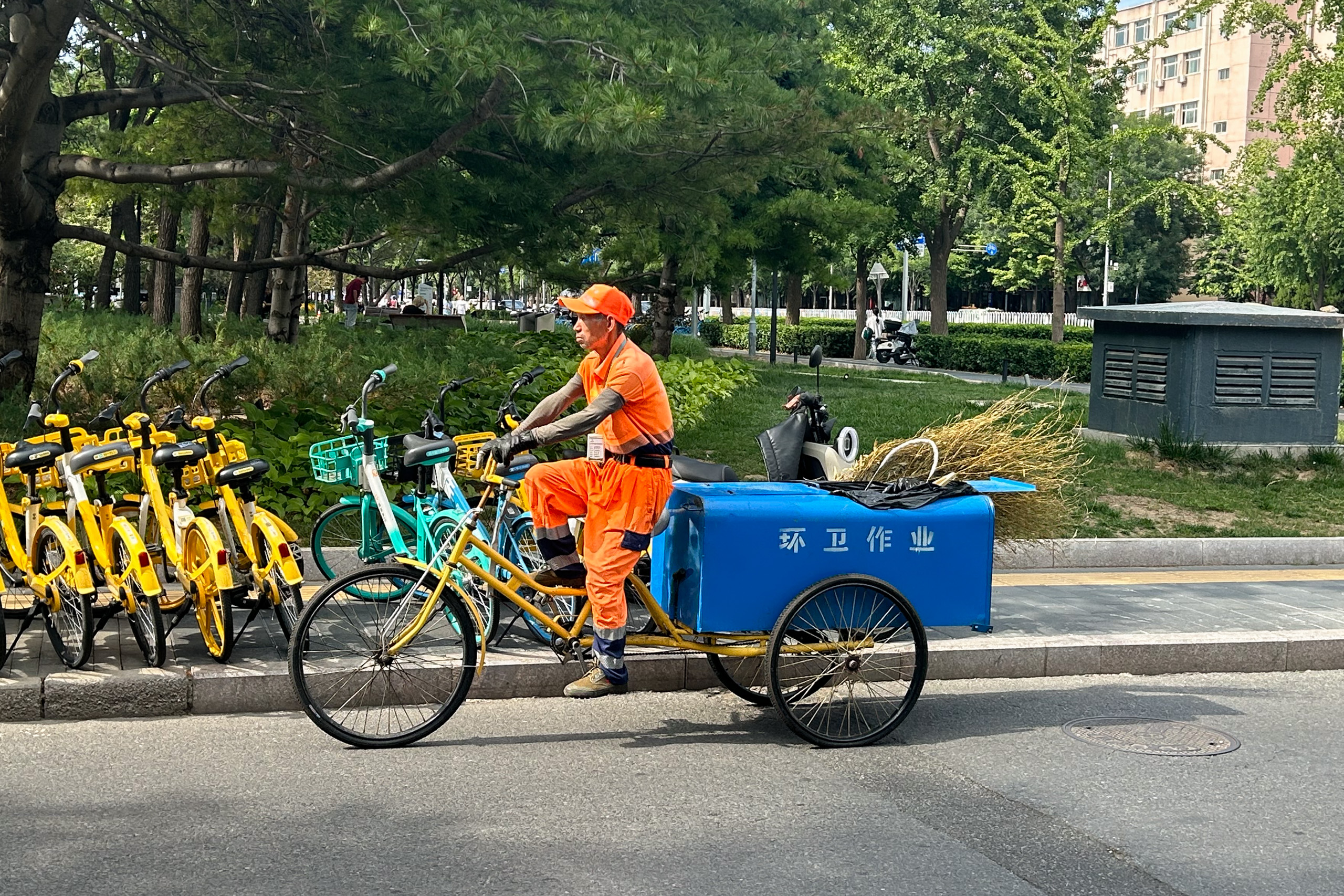 A street sanitation worker wears long-sleeved clothing and gloves to protect his arms against the fierce sun 