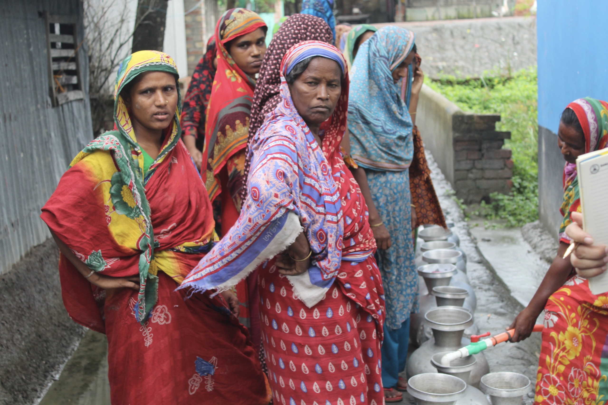 women waiting in line to vill water vessels