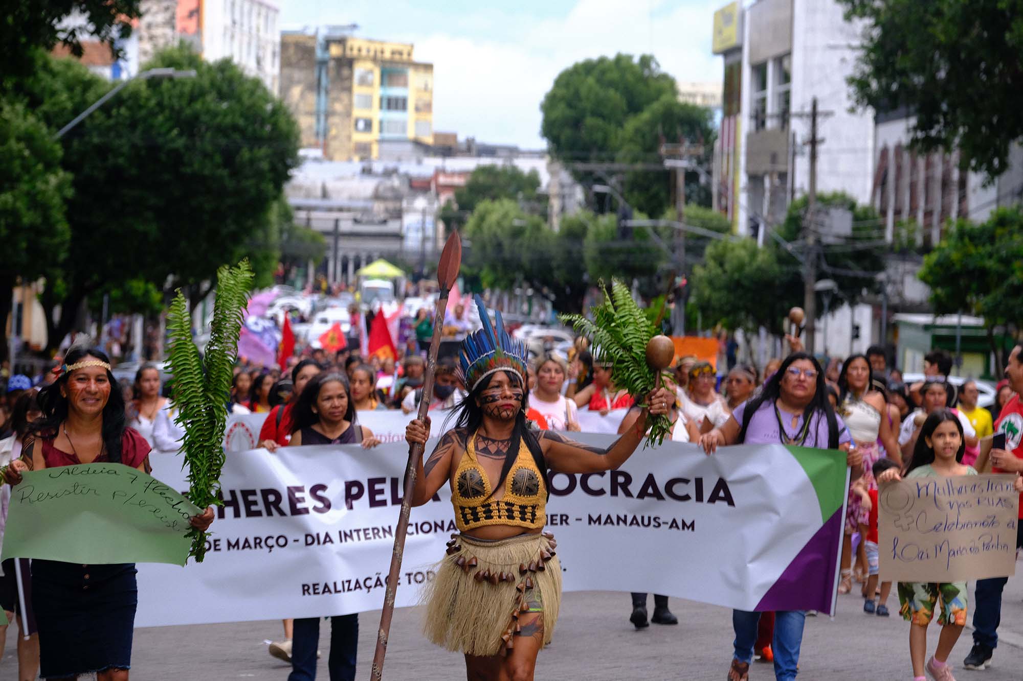 large group of women with banners and signs march down street