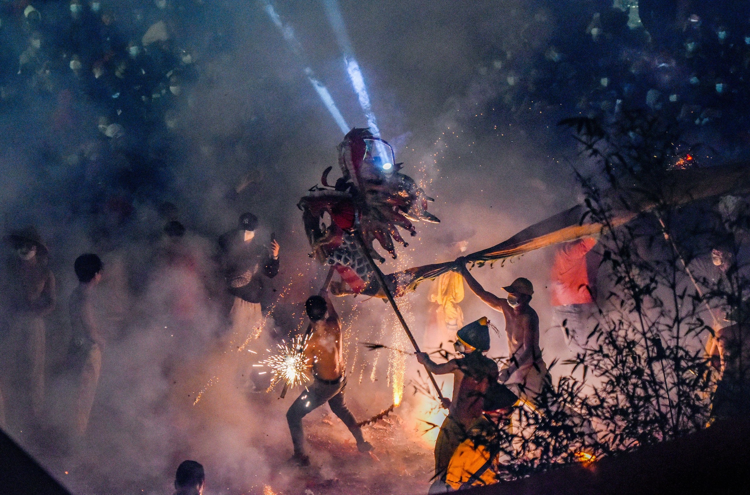 A group of people stands around a fire performance dragon dance