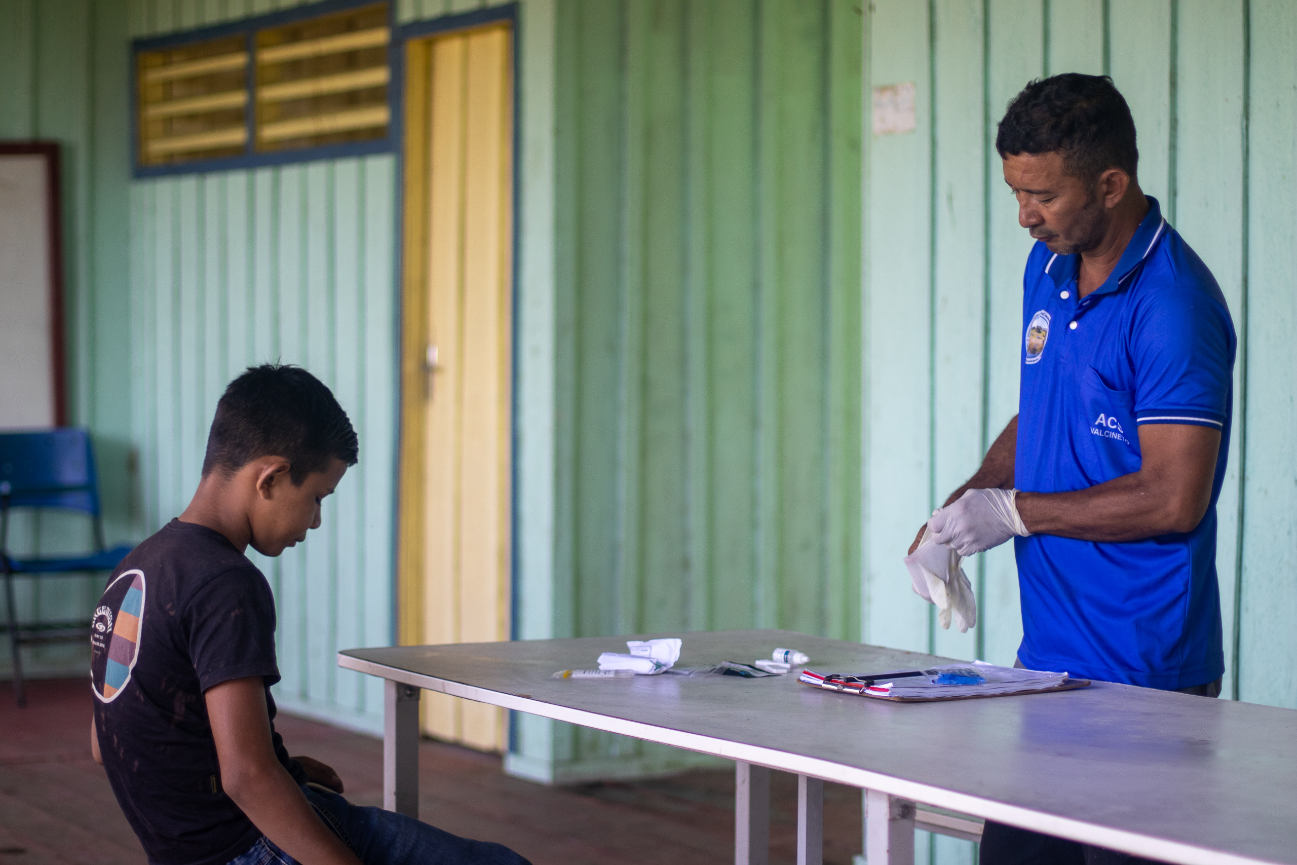seated child facing standing man putting on gloves
