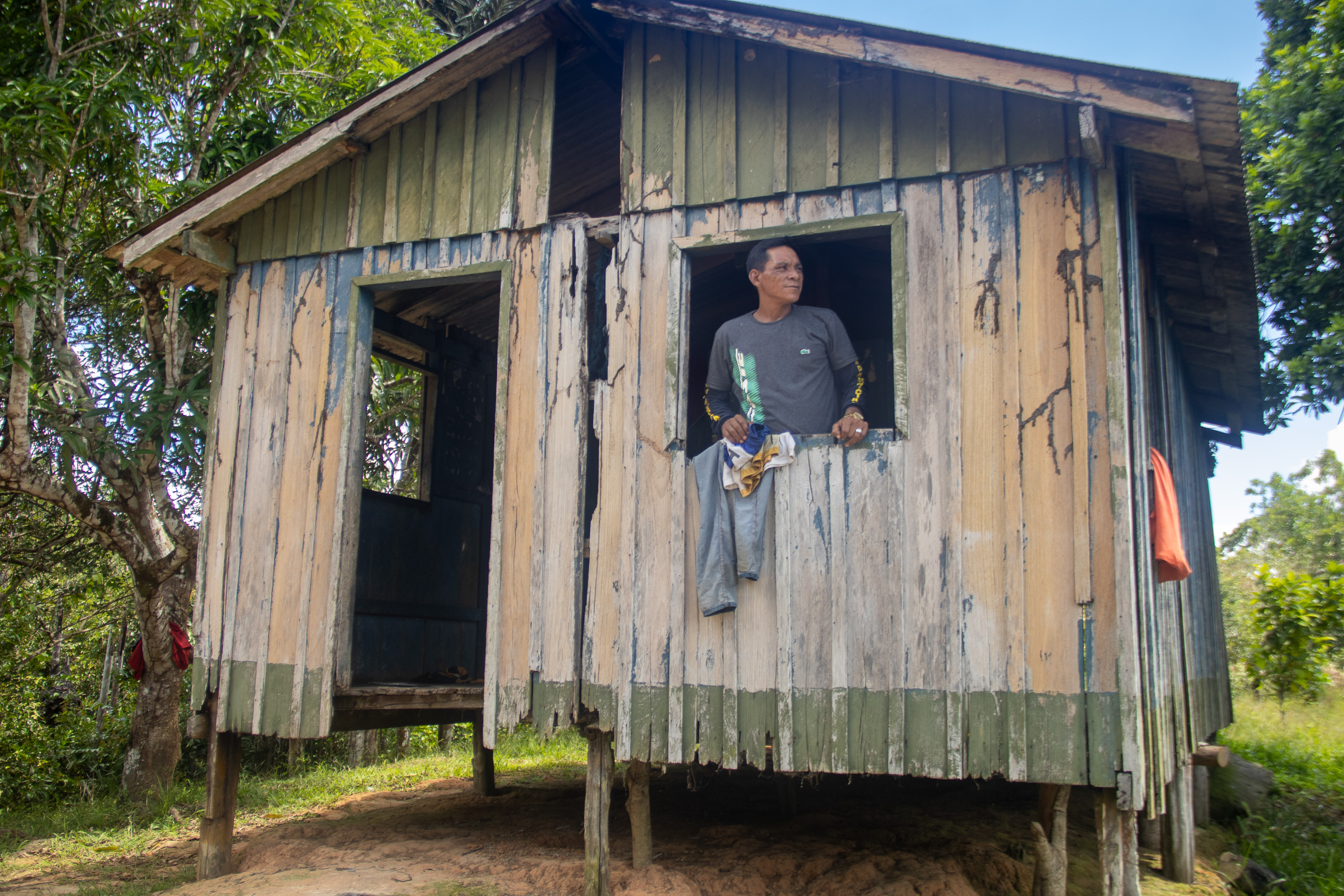 man looking out of window of wooden housse