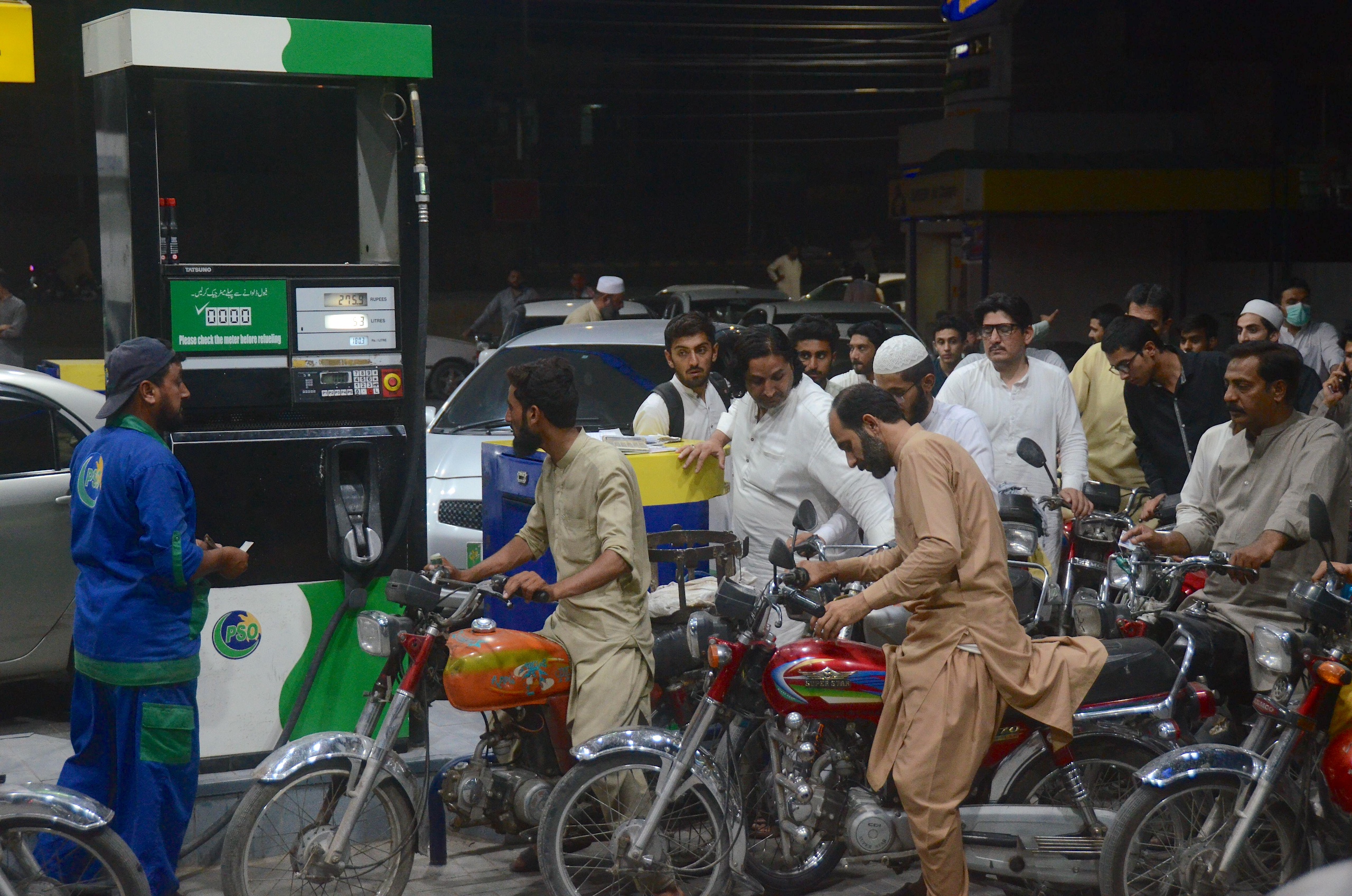 Motorists wait to fill their vehicles' tanks at a petrol station