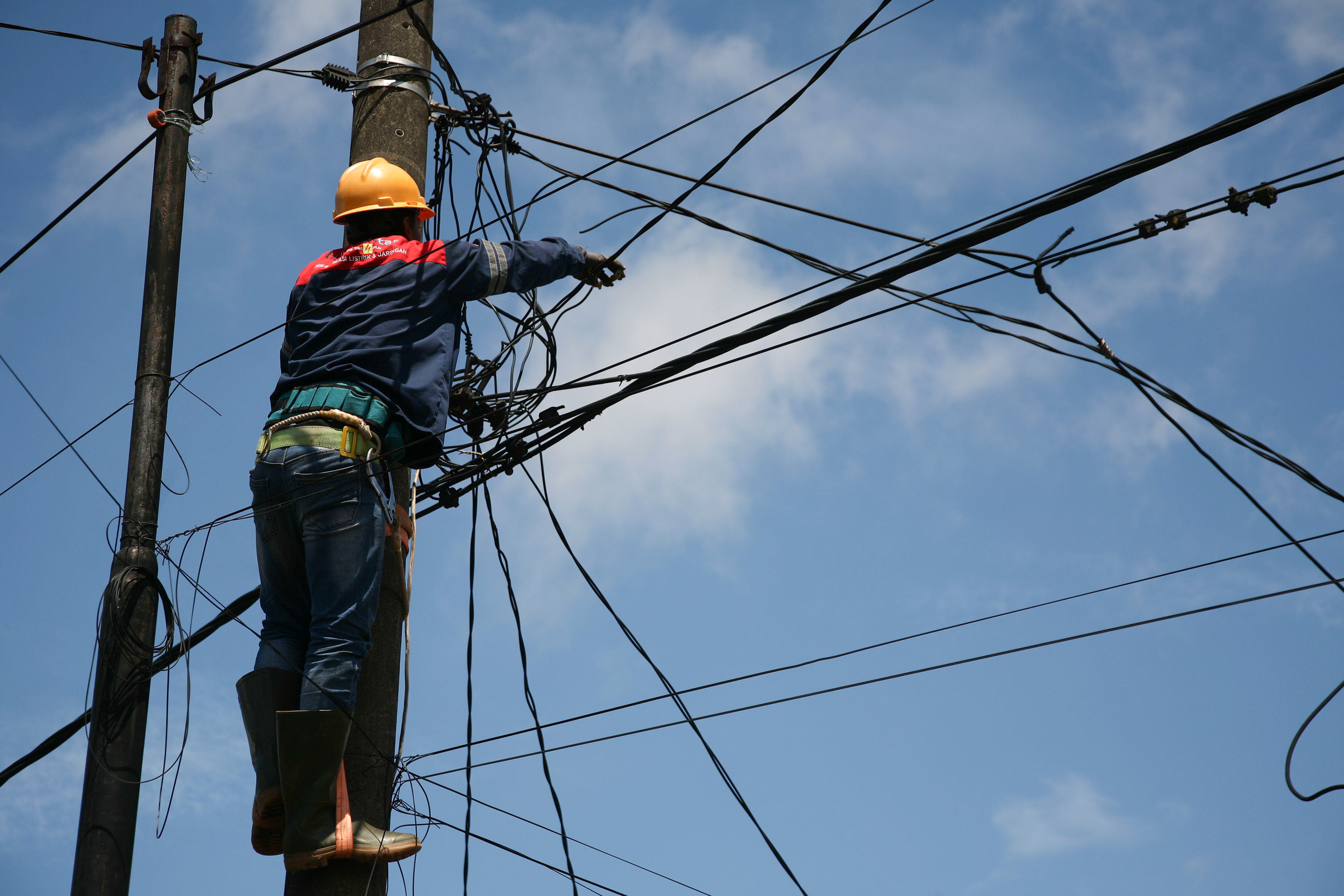 <p>Workers repair the household electricity network in Bogor, Indonesia (Image: Kuncoro Widyo Rumpoko / Pacific Press / Alamy)</p>