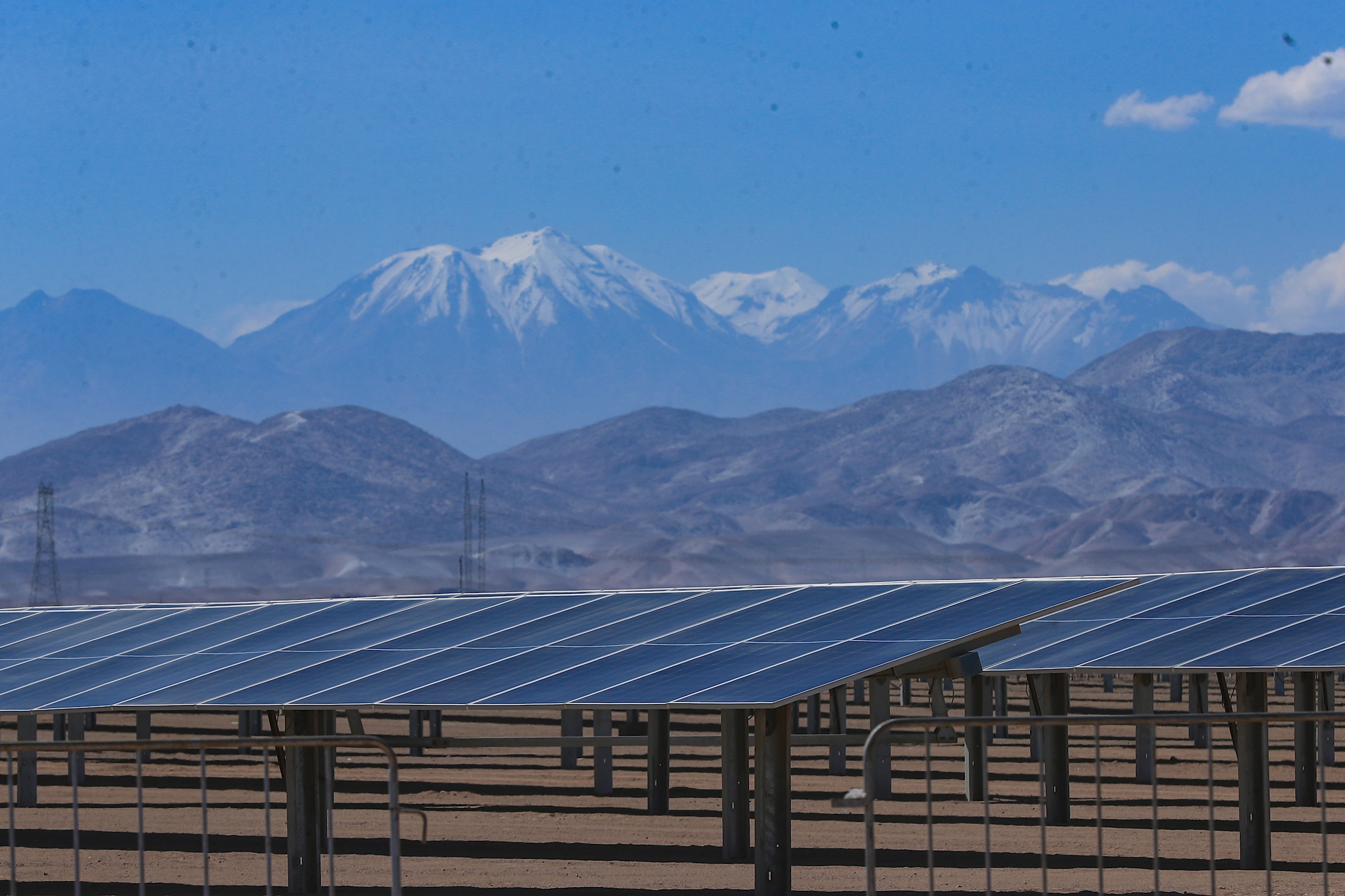 Painéis solares no deserto, com montanhas nevadas ao fundo
