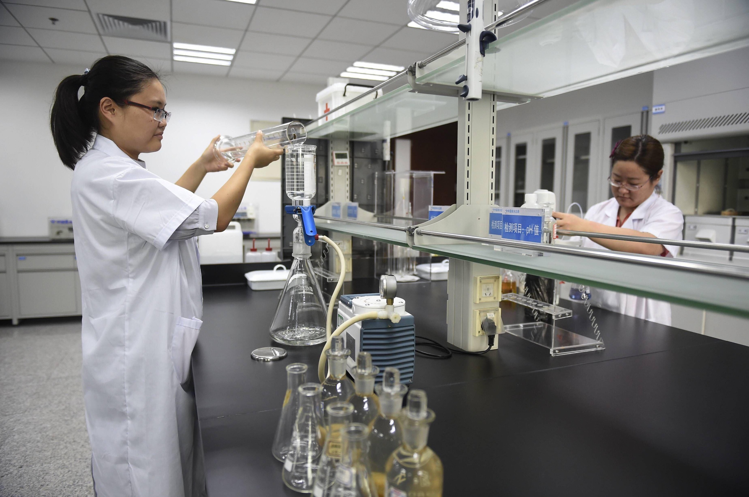 Two female analysts check the water sample at a lab