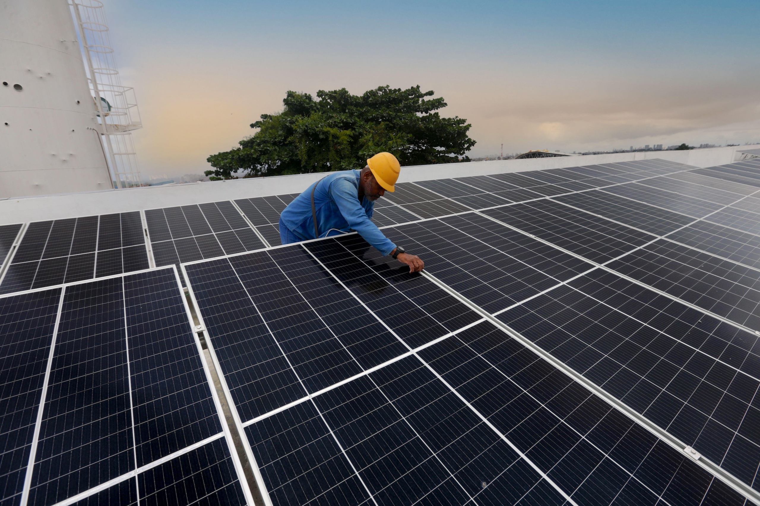 Um trabalhador instalando painéis solares em um telhado
