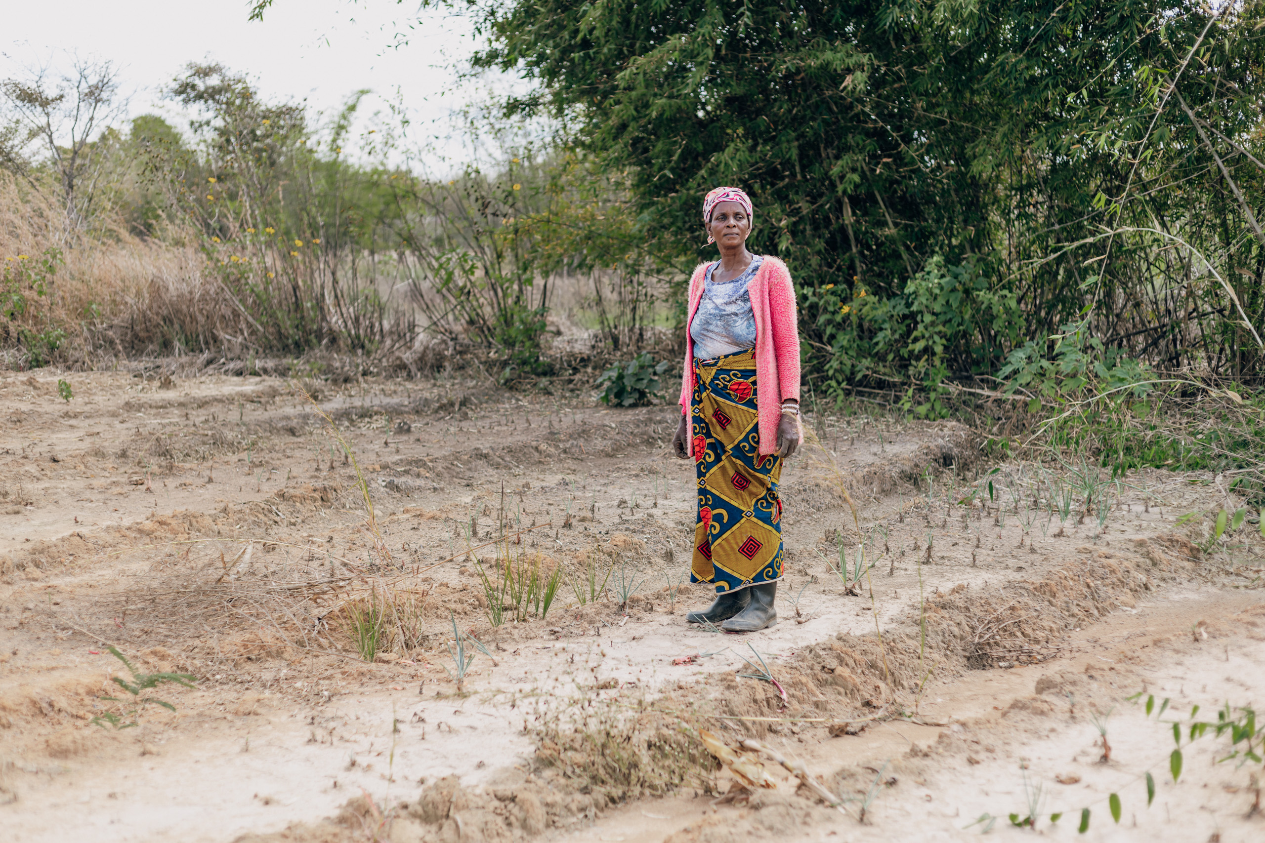 A woman stands in a dry ruined field