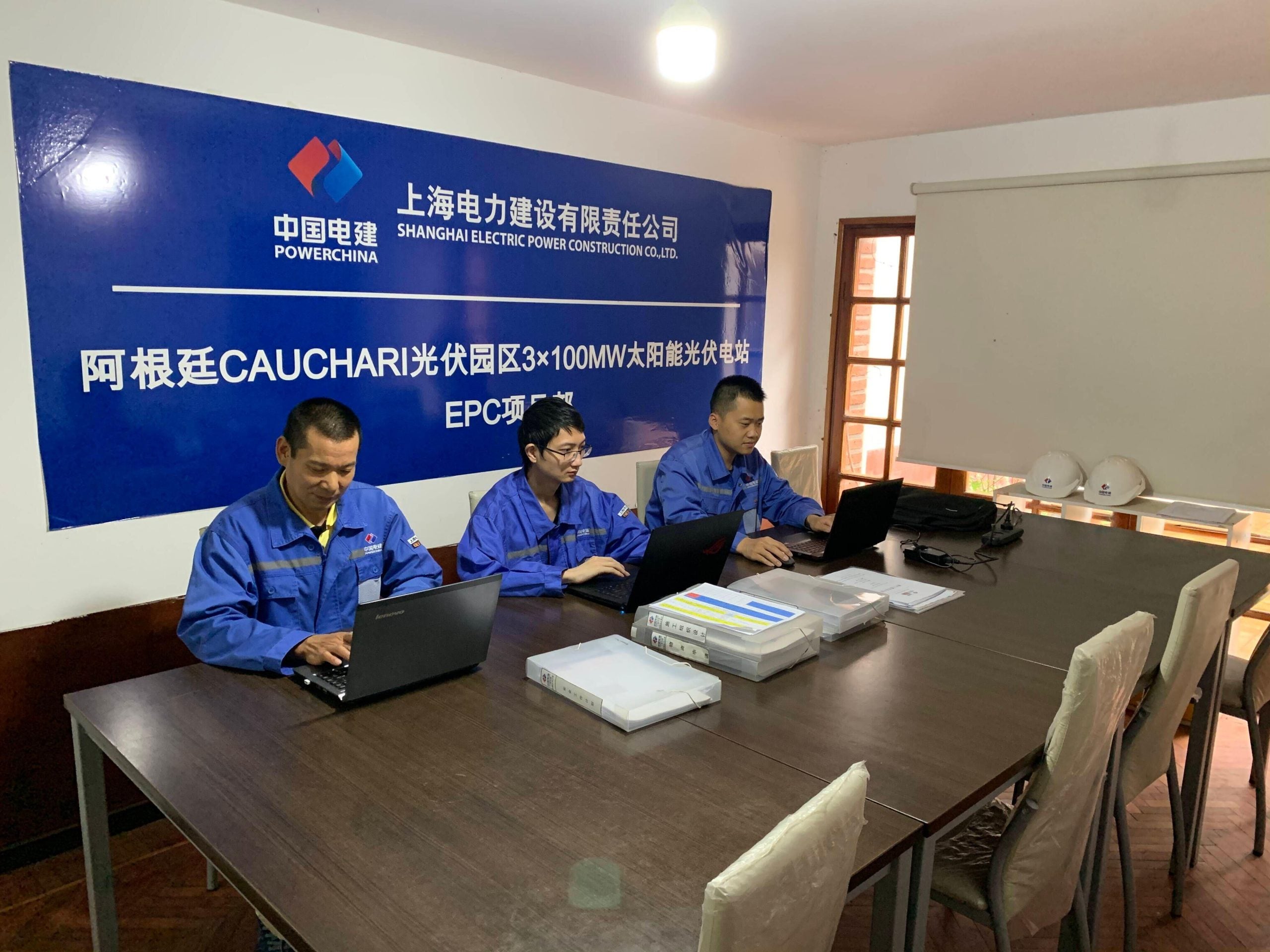 three people with laptops at large desk