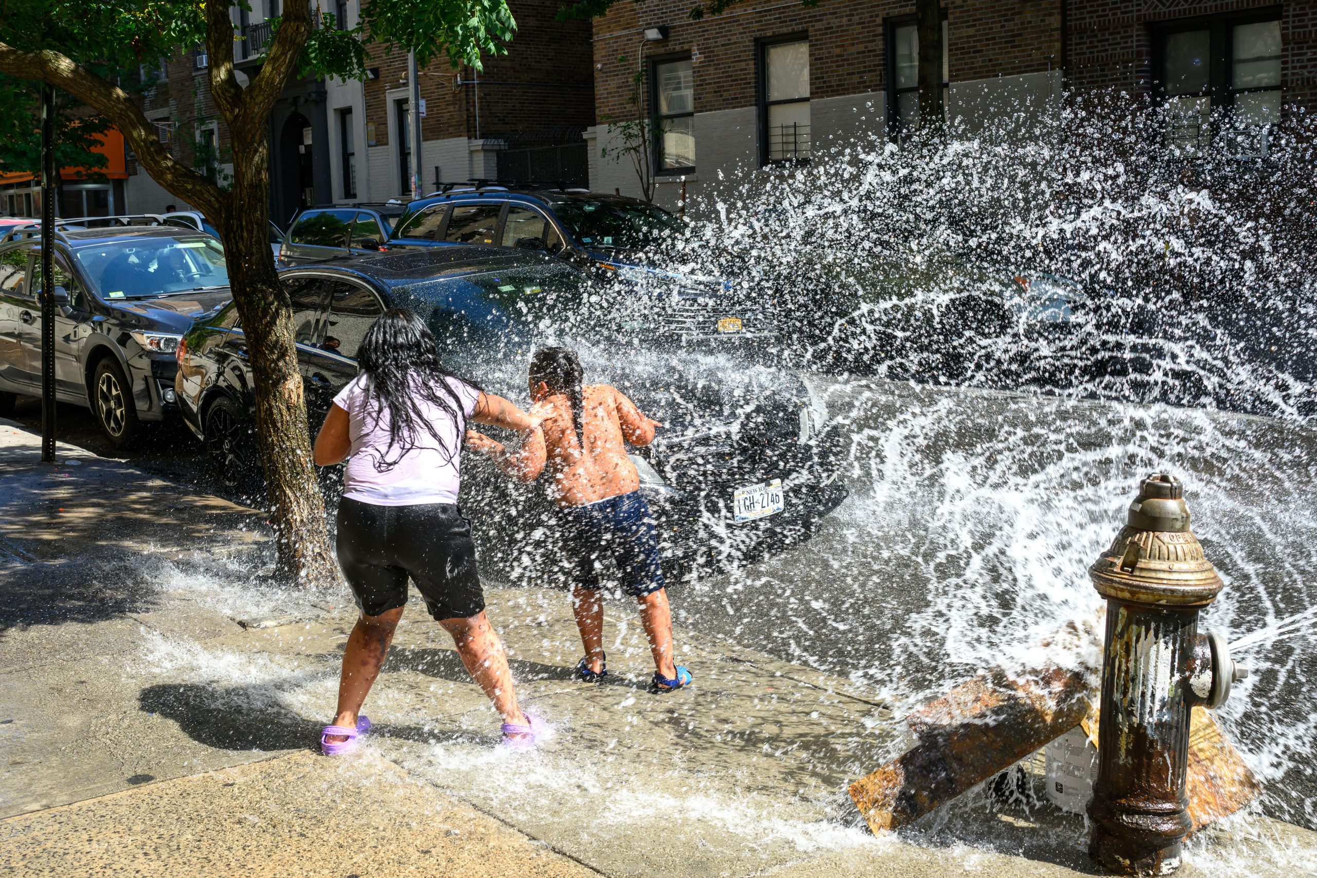 Children play with water spray from open fire hydrant