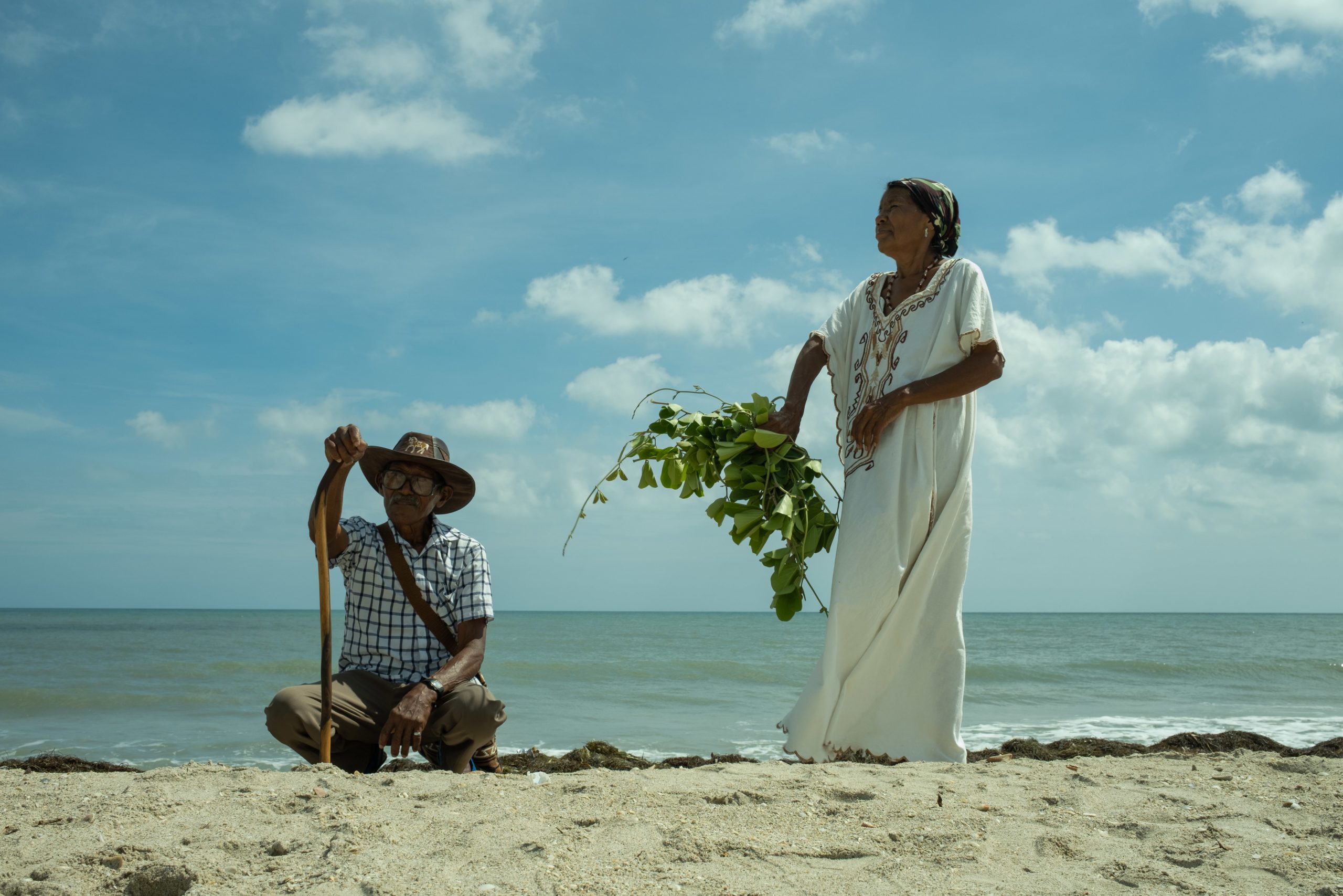 man squatting and woman standing on beach