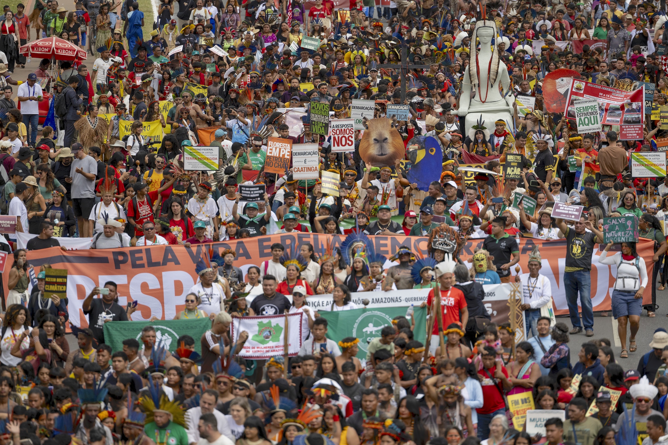 A large, vibrant crowd of activists holding signs and banners, advocating for environmental protection and indigenous rights