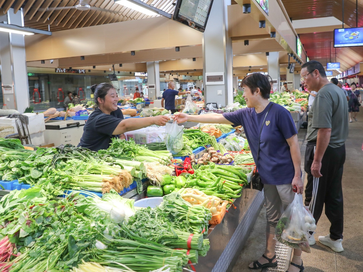 People shop for vegetables at an indoor market
