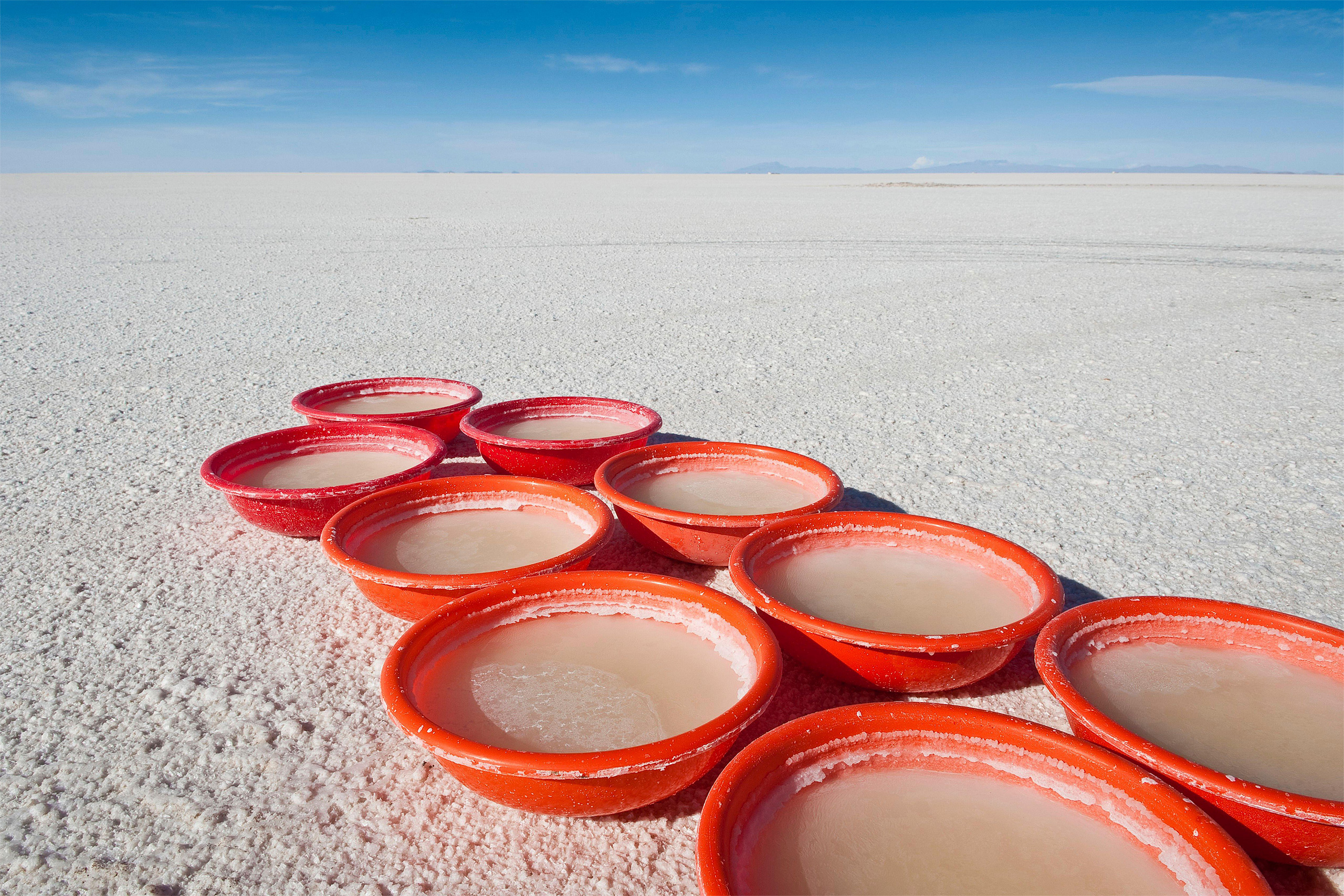 row of shallow basins filled with cloudy liquid on fine sand