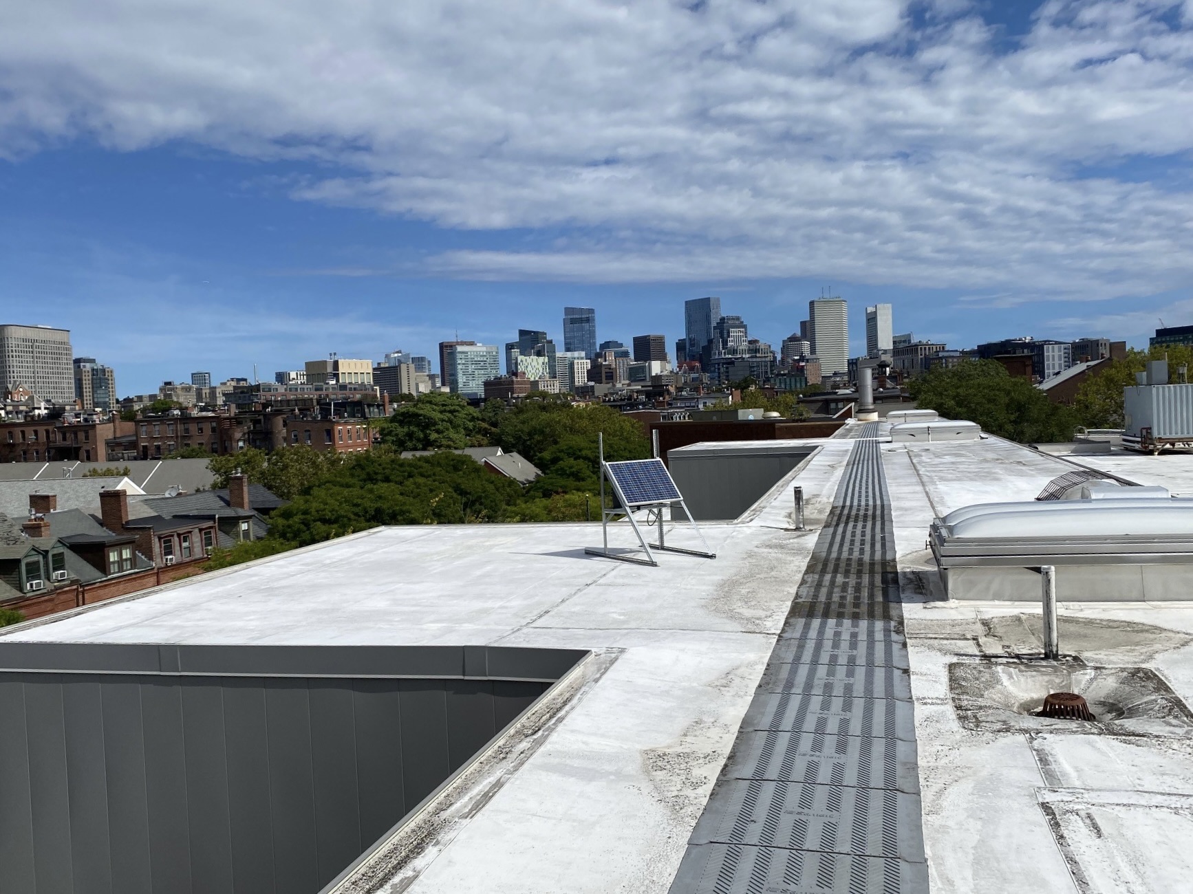 View from a rooftop with a solar panel, overlooking a city skyline