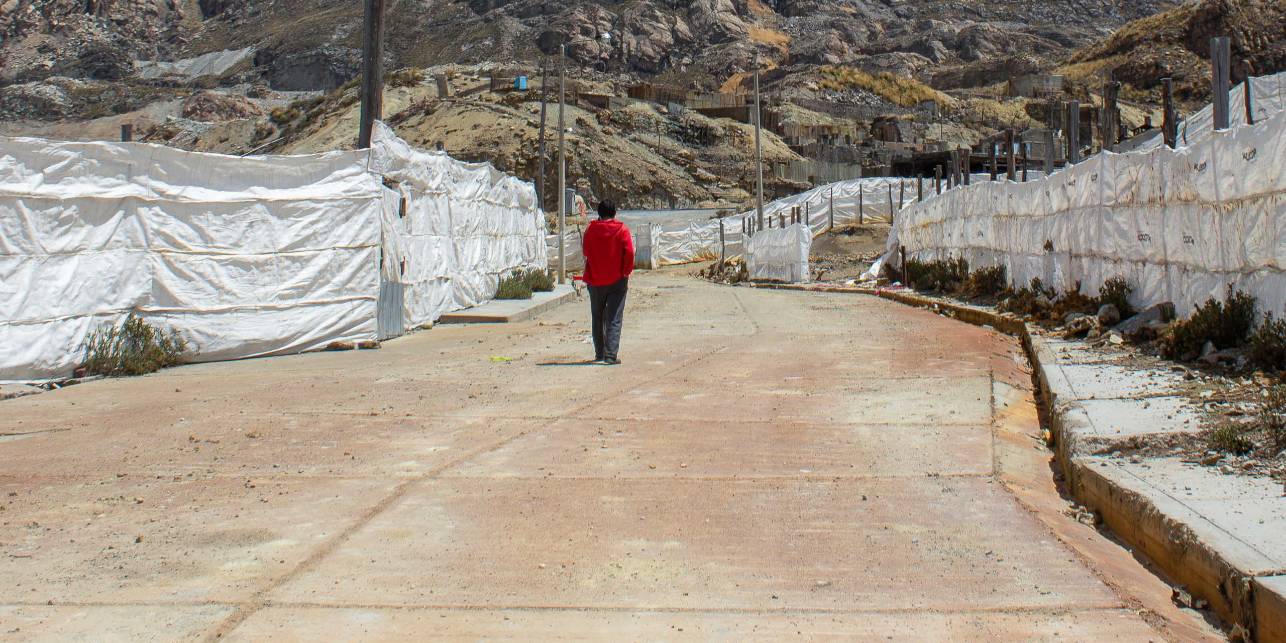 <p>Elvis Atachahua Ursua, who was one of the last residents of Morococha, walks through the damaged streets of the town two months before he was evicted. His eviction, along with that of the last few families living in the town, has paved the way for mining at Toromocho, one of the largest copper projects in Peru, by the Aluminum Corporation of China (Image: Sally Jabiel)</p>