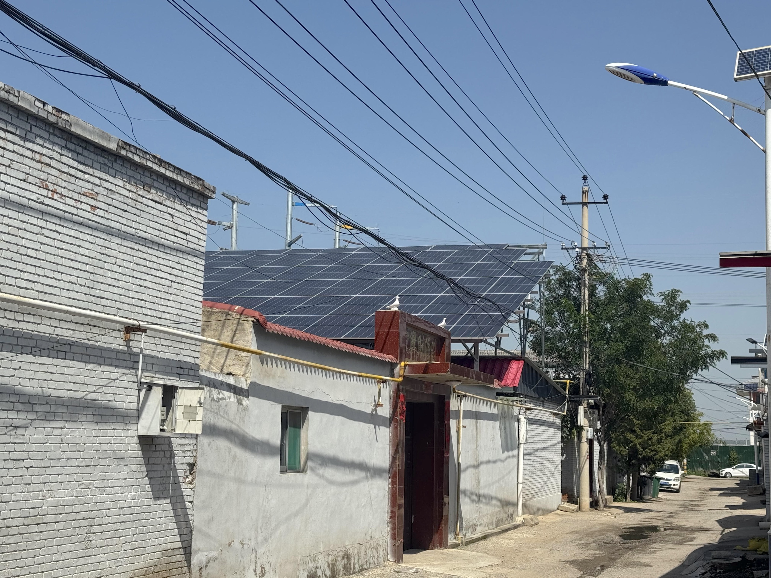 A narrow street lined with buildings features a solar panel array on the roof