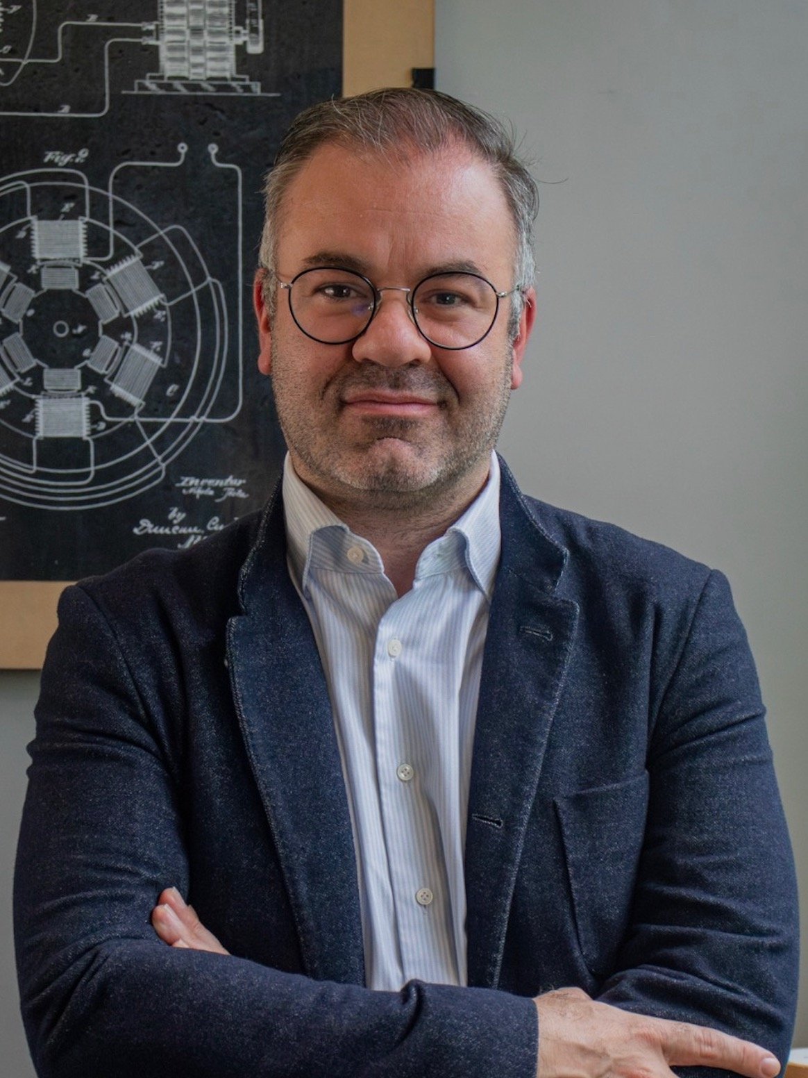 Eugenio Grandío, homem de meia idade com óculos, cabelo e barba grisalhos e terno