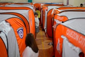 A woman walks beside tents at an evacuation center