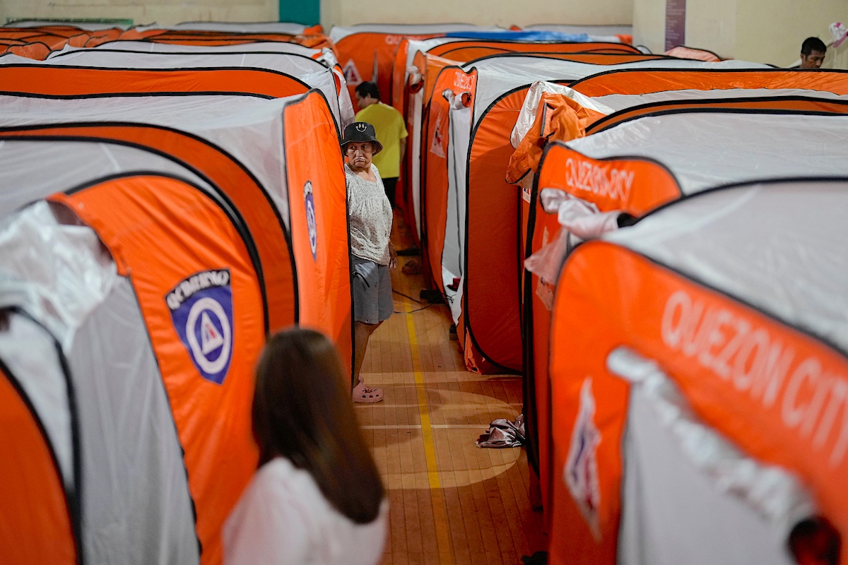 A woman walks beside tents at an evacuation center