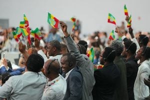 A diverse group of people waves Ethiopian flags during a COP30 event