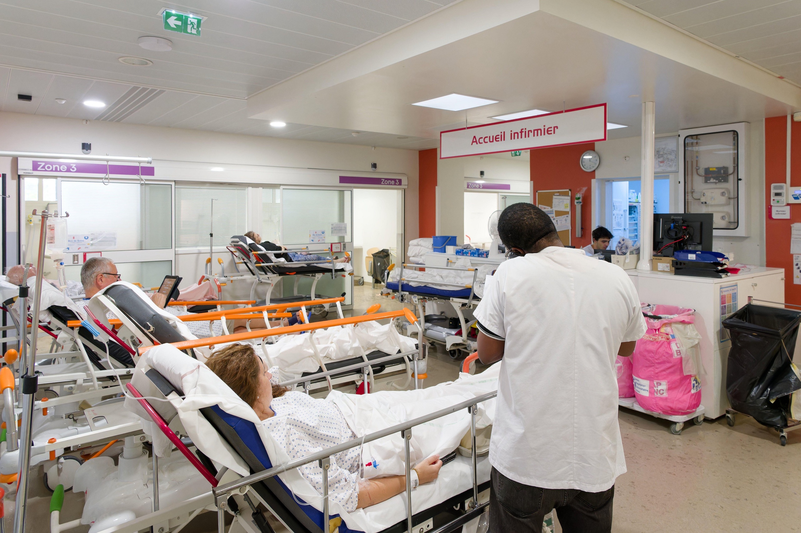 A busy hospital ward with patients in beds, medical staff attending to them