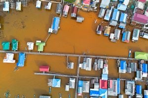 Aerial view of houses on stilts surrounded by murky brown water