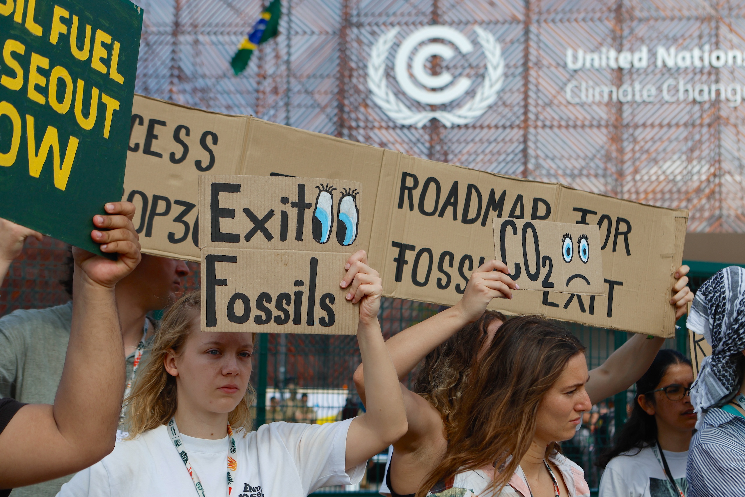 Protesters hold signs advocating for the end of fossil fuels at COP30