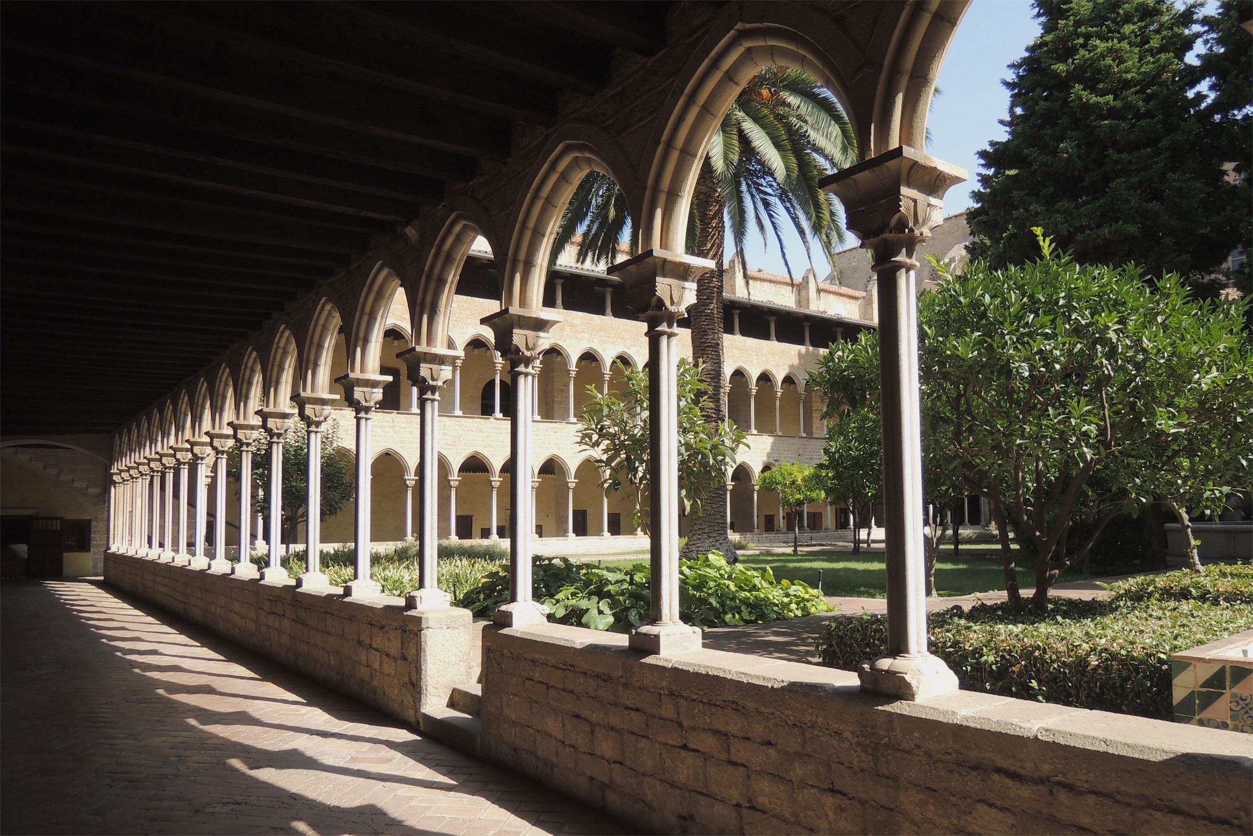 A courtyard with arched stone columns and trees