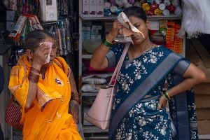 two women wipe the sweat from their faces in front of a store