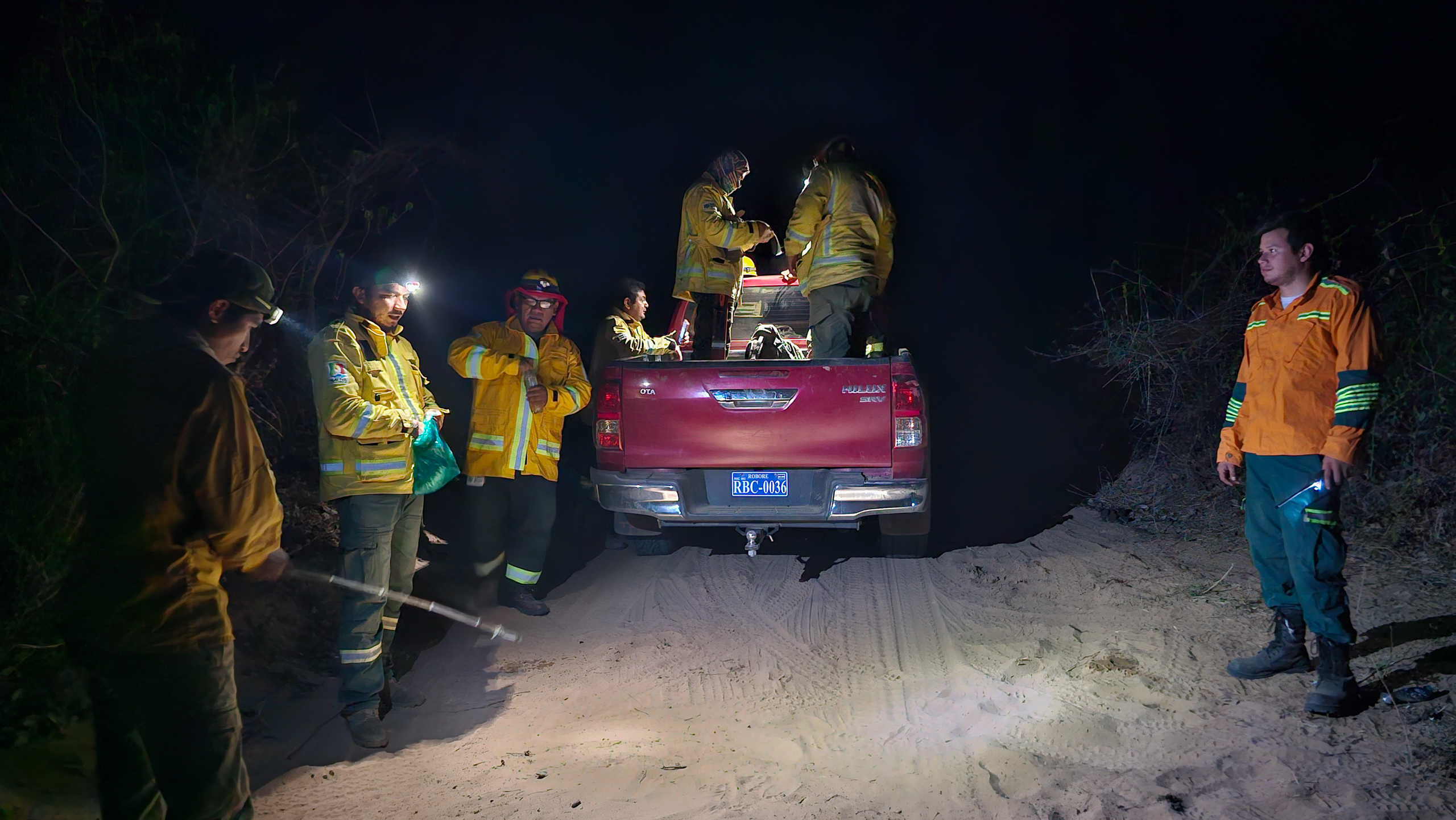 Bomberos en una carretera de tierra de noche